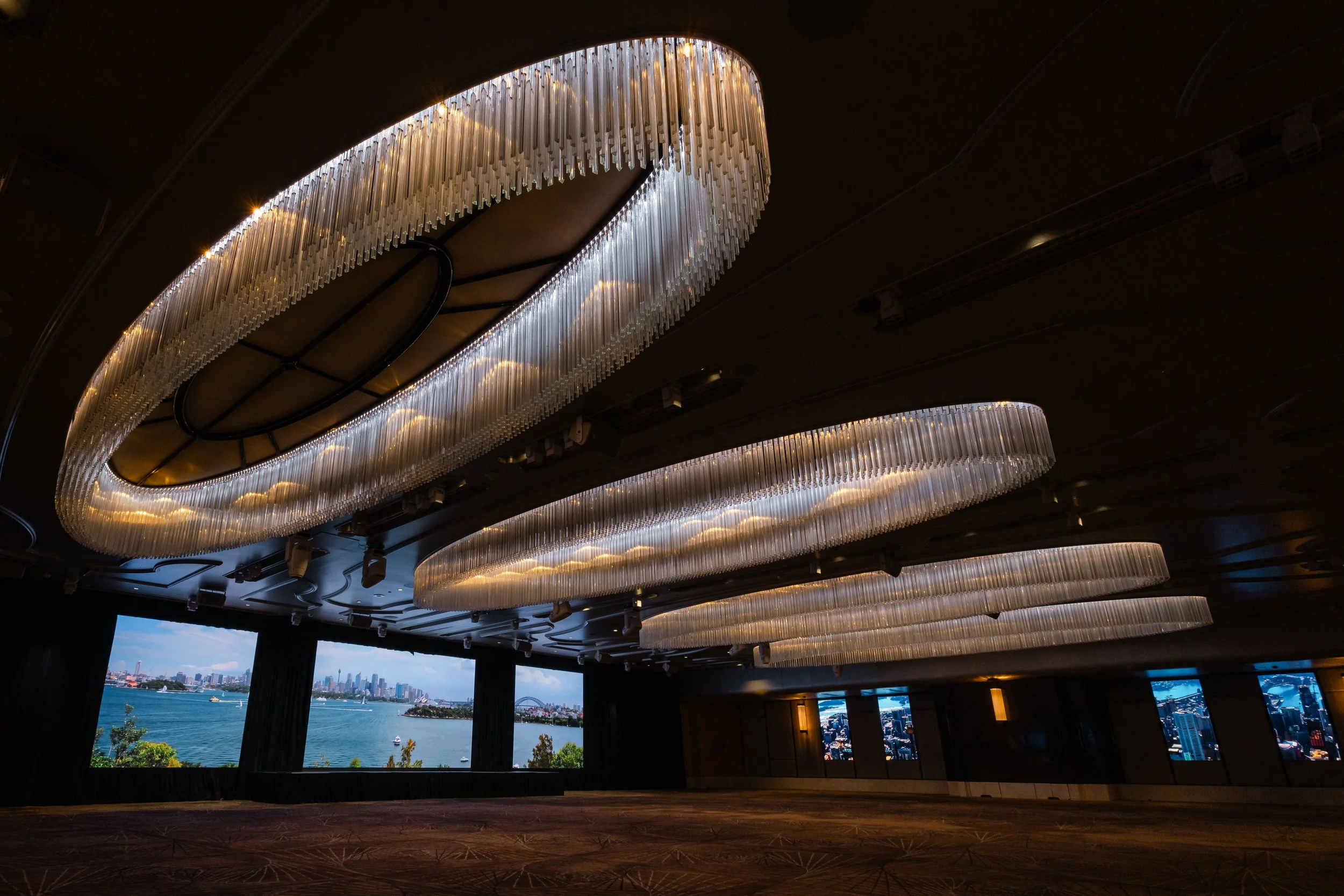 The Grand Ballroom at Shangri-La Hotel, Sydney in warm white light, with the chandeliers lit and screens on the walls