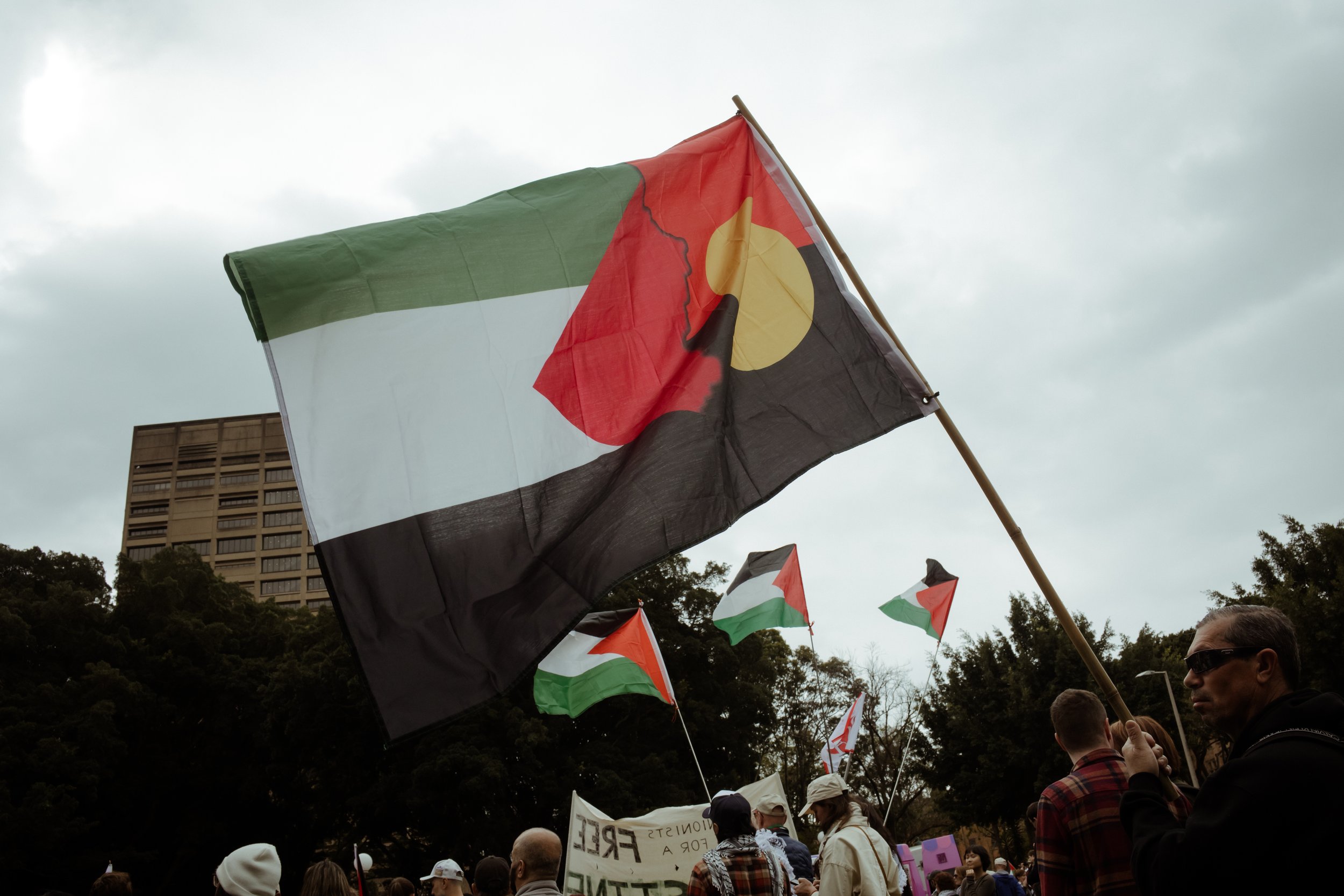 A combined Aboriginal and Palestinian flag flying over the march from Hyde Park, Sydney