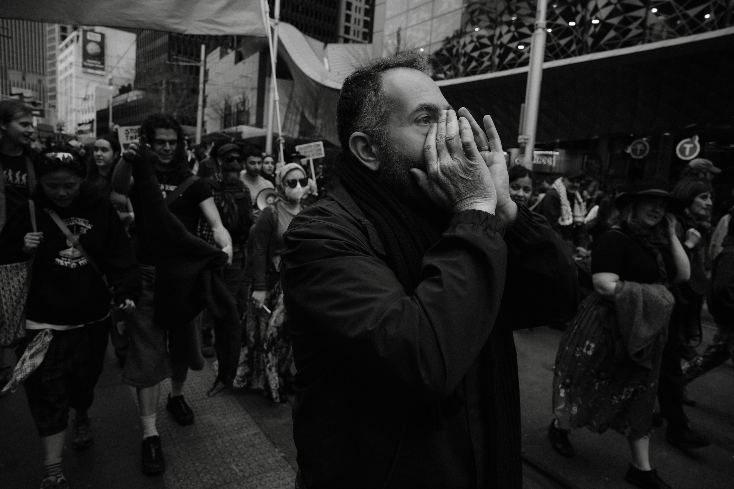 Black and white frame of a man shouting with his hands cupped