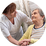 Nurse gently holding hands with an elderly woman in a wheelchair.