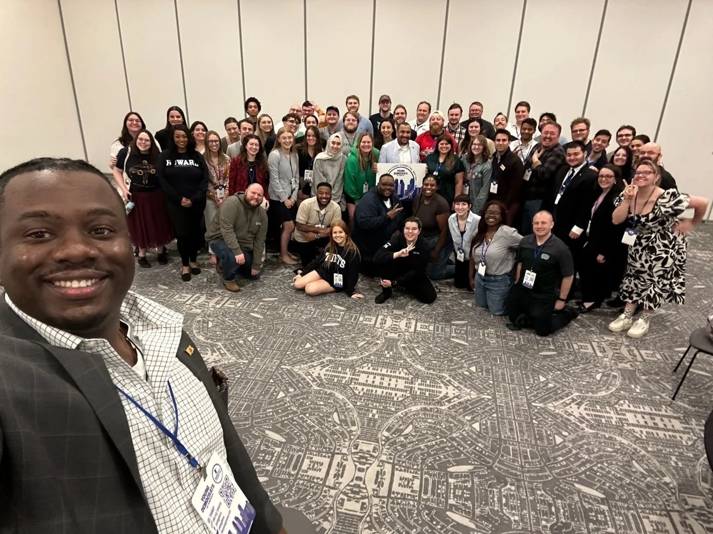 Group of diverse people gathered together for a photo in a conference room with Christian Seale, candidate for El Paso County Commissioner District 5, with a man taking a selfie in the foreground.