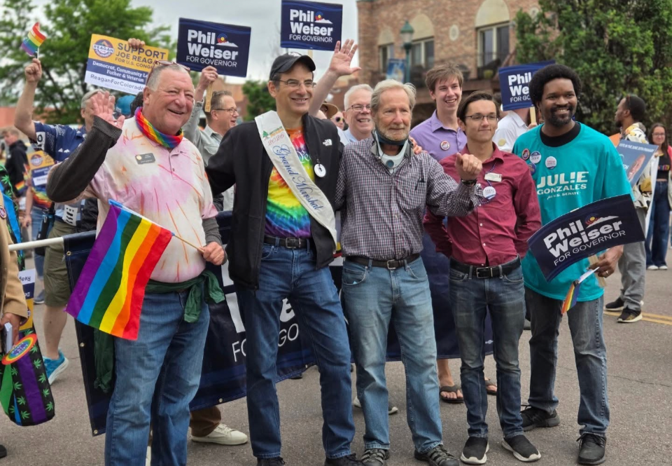 Christian Seale candidate for el paso county commissioner district 5  and Group of people at an LGBTQ+ pride parade holding signs and rainbow flags, smiling and celebrating.