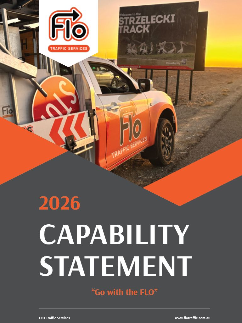 A vehicle with FLO Traffic Services branding parked on the side of a road near a billboard that welcomes to the Strelecki Track during sunset.