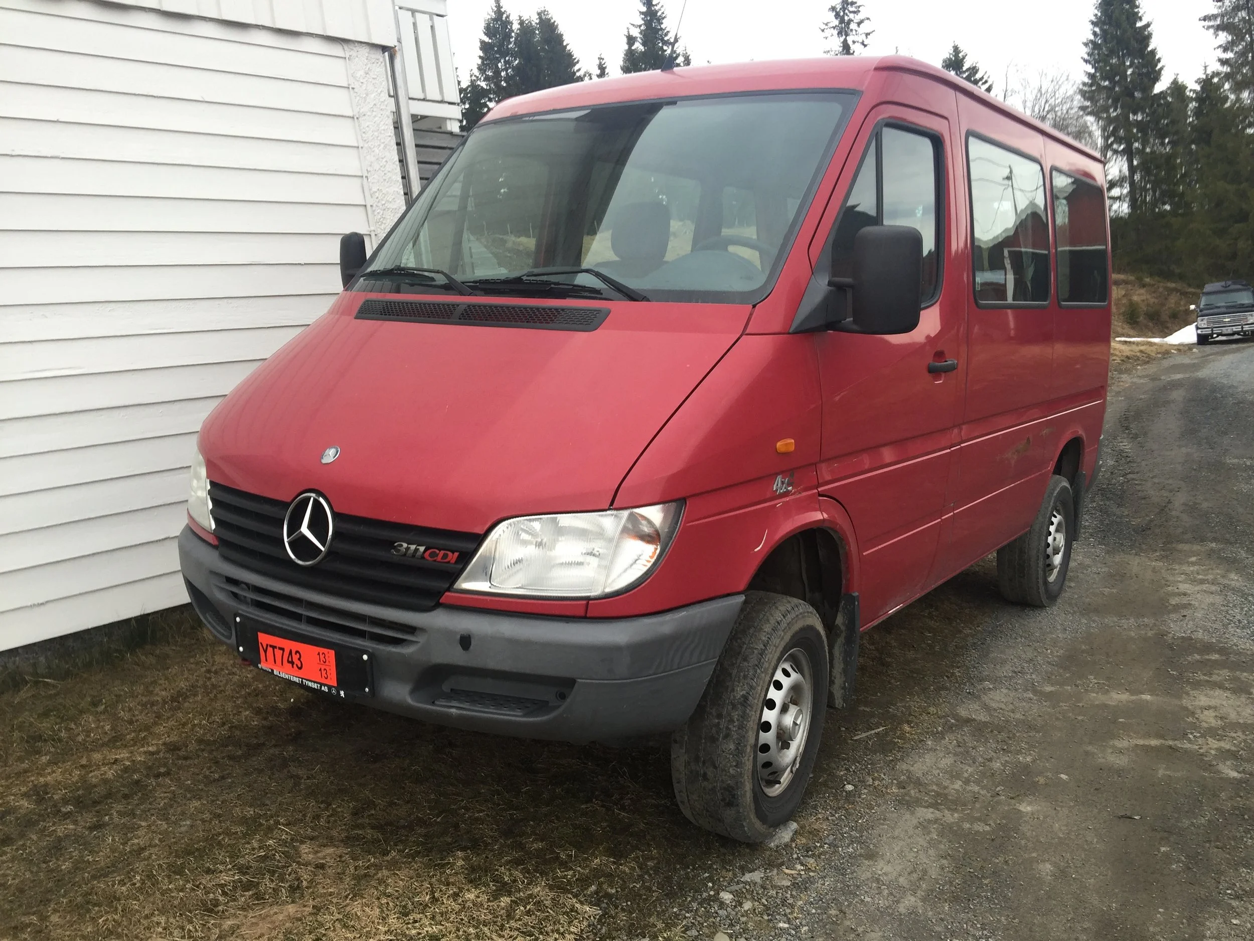 Red Mercedes-Benz Sprinter van parked on a gravel drive waiting to become the green PhotoVan.