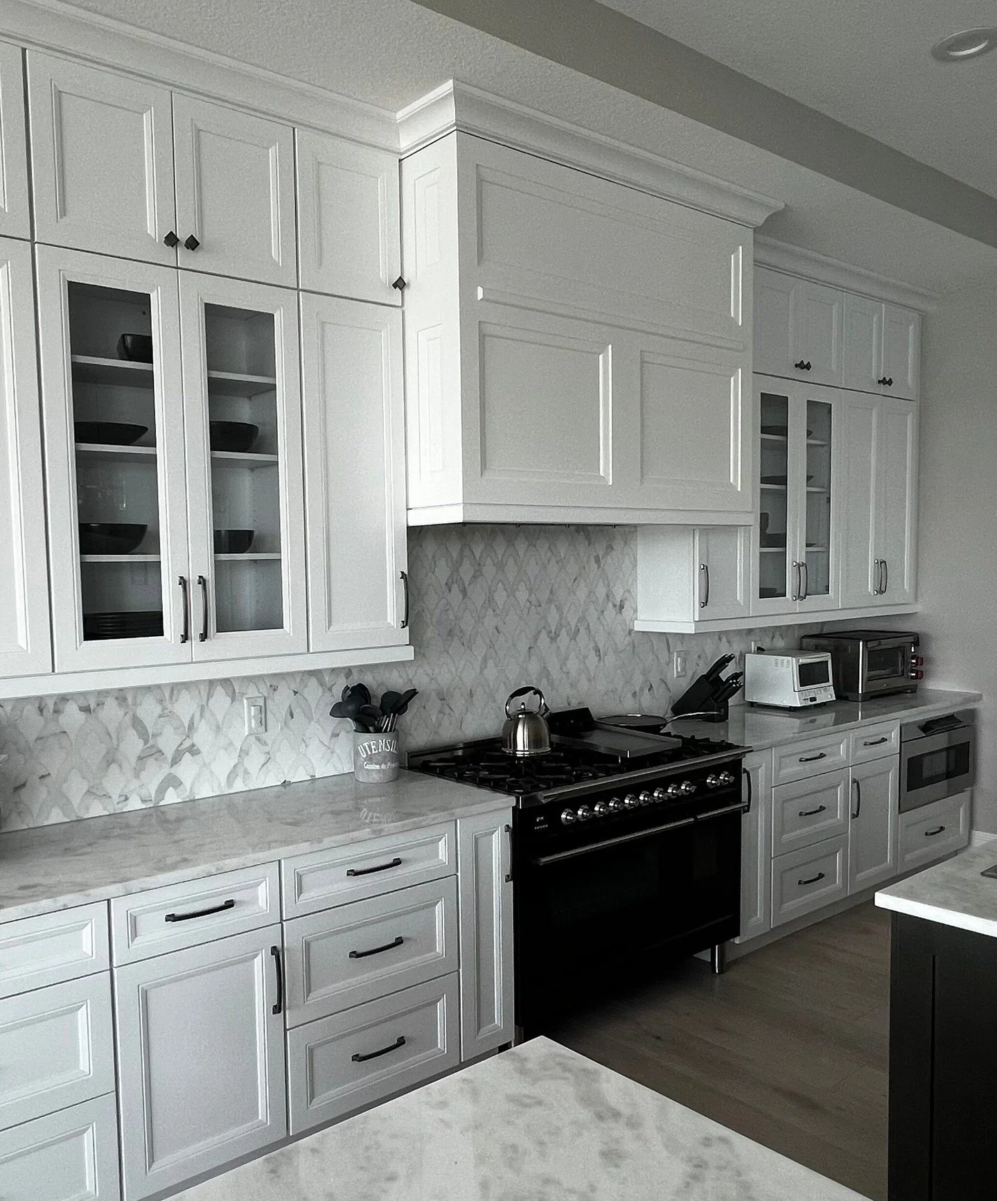 A box hood that matches the surrounding cabinetry allows the range wall to read as one cohesive composition. 

The hood becomes part of the architectural rhythm of the cabinets. Matching door profiles, paint finishes and crown lines help the hood ble