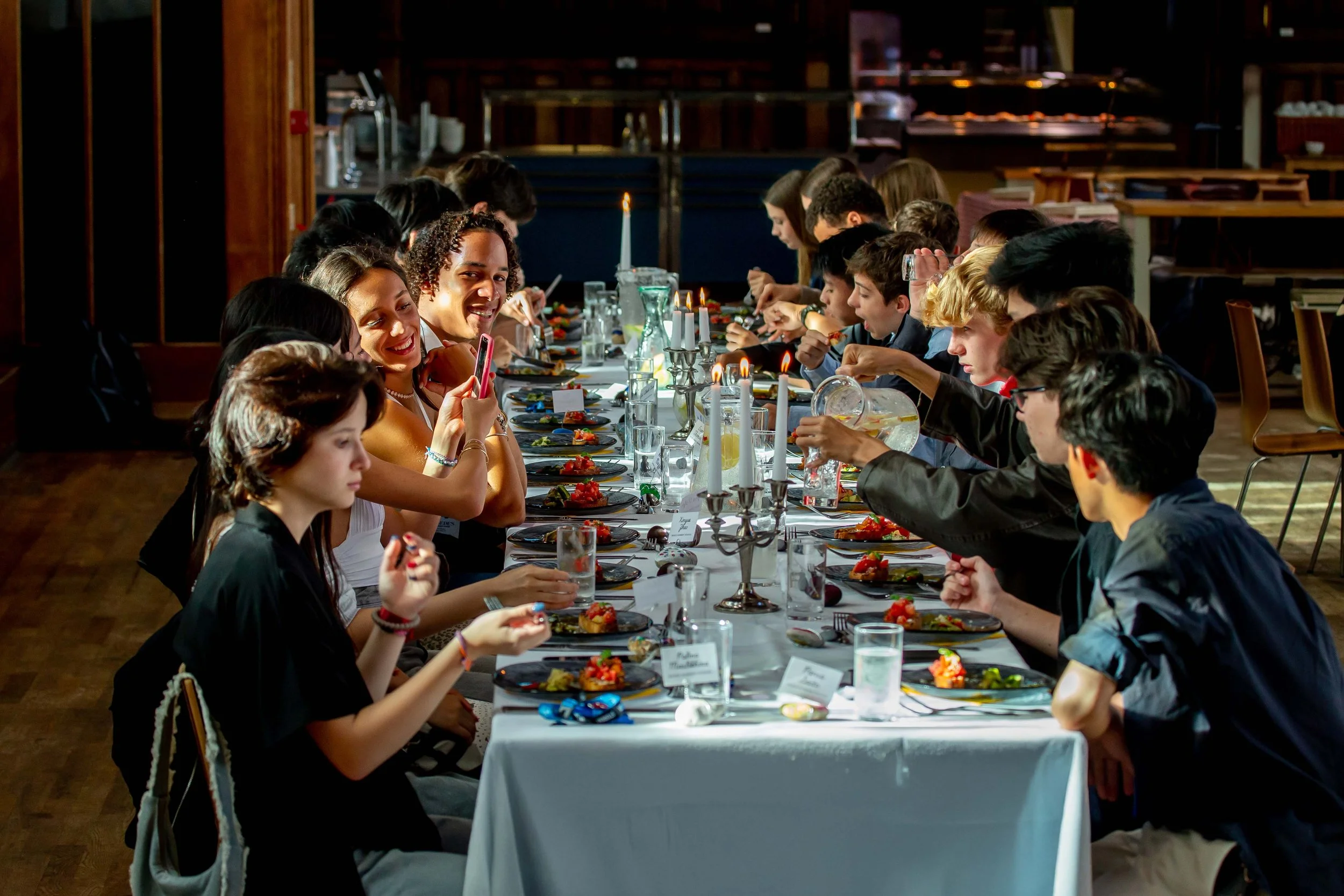 Jóvenes disfrutando de una cena especial en un comedor británico durante un campamento de verano, compartiendo experiencias culturales y haciendo nuevos amigos.