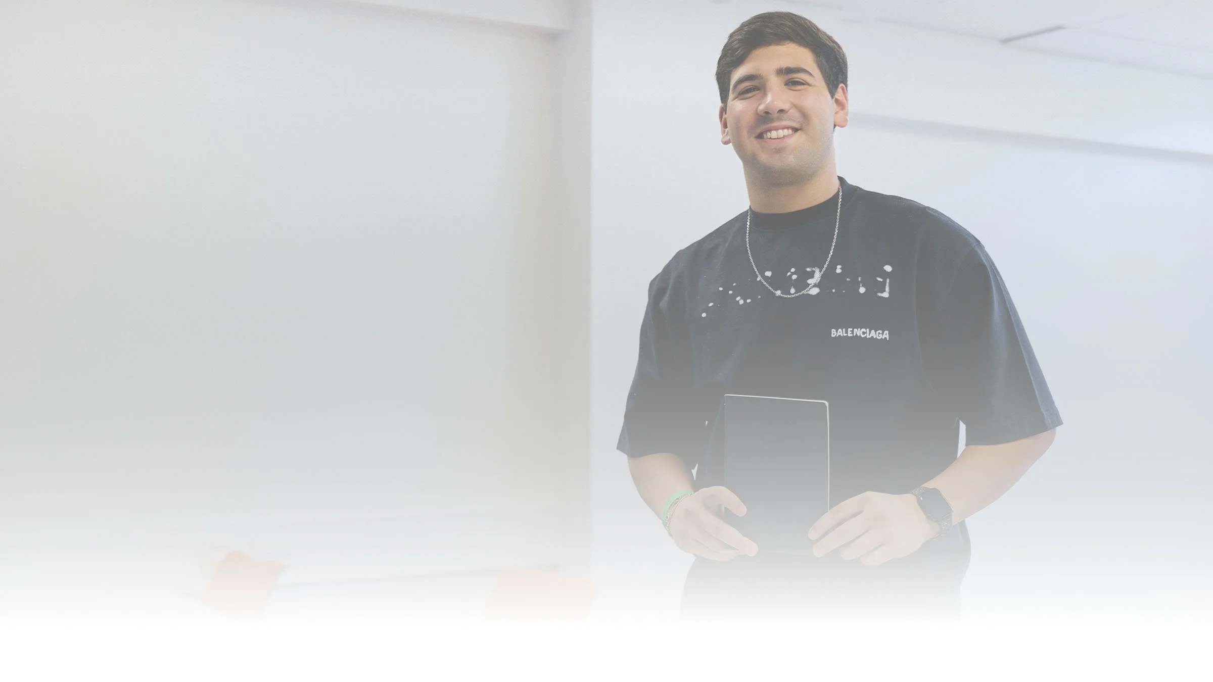 Joven sonriente sosteniendo una tableta electrónica en un espacio interior luminoso.