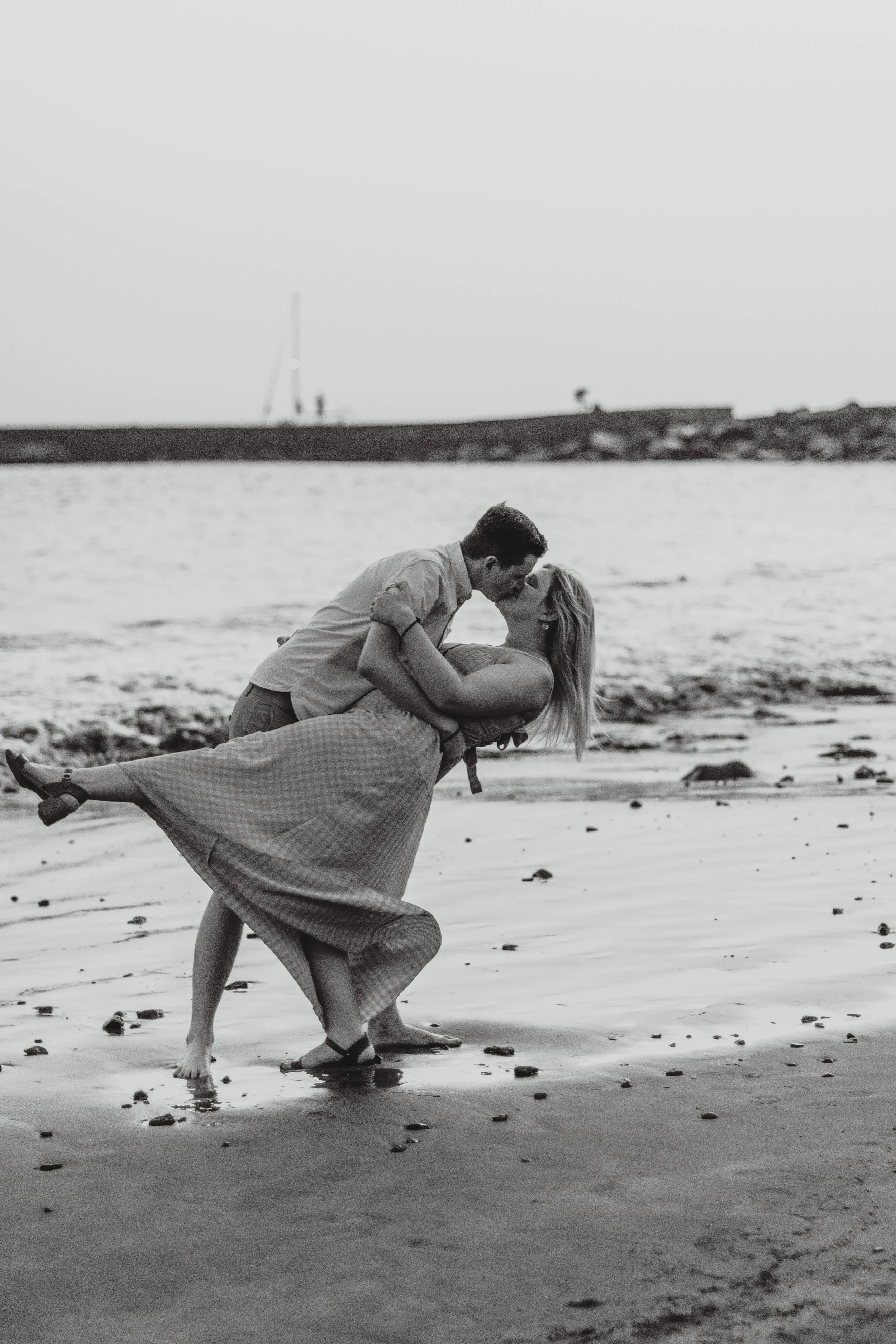 Couple kissing and dancing on a sandy beach.