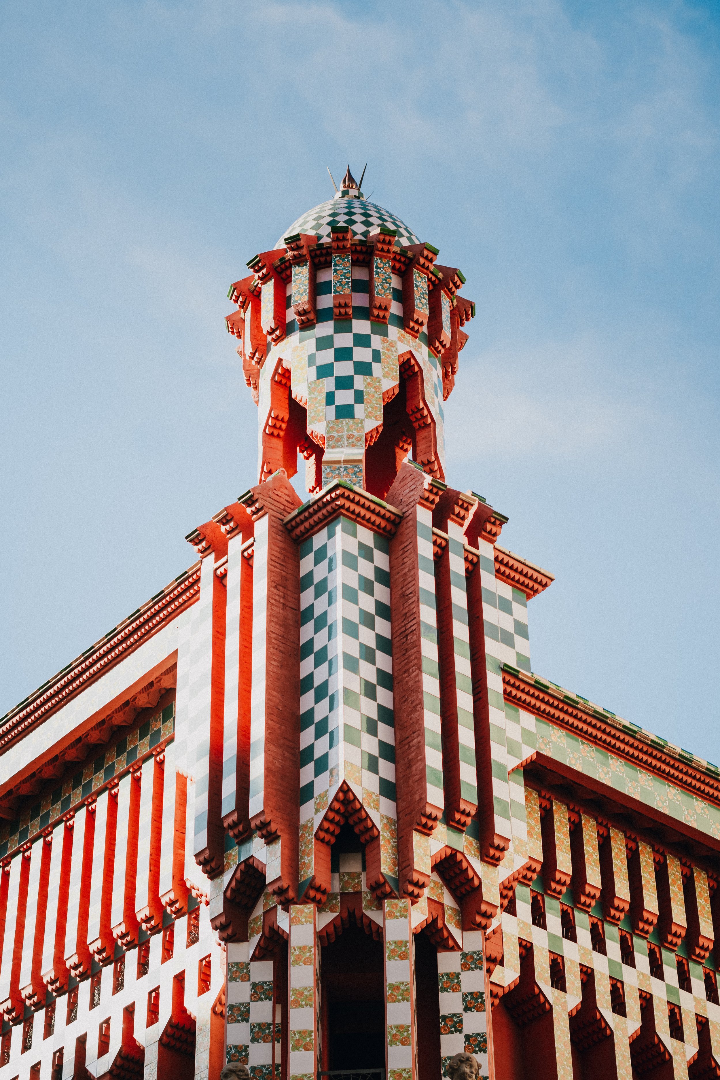 Colorful section of Casa Vicens in Barcelona, featuring checkered patterns and ornate architectural details against a clear blue sky.