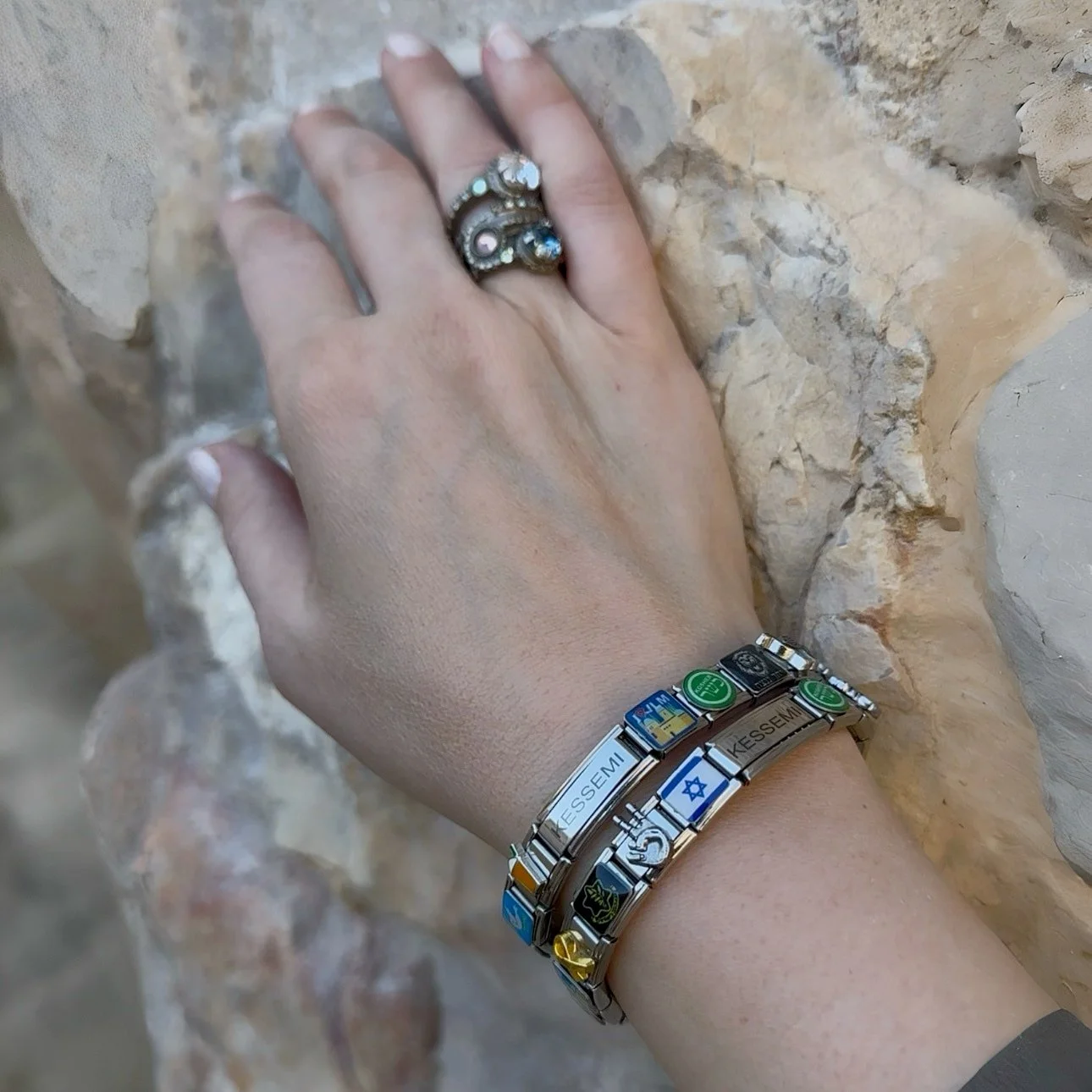 a hand reaching out to pray at the kotel or western wall wearing kessemi charm bracelets