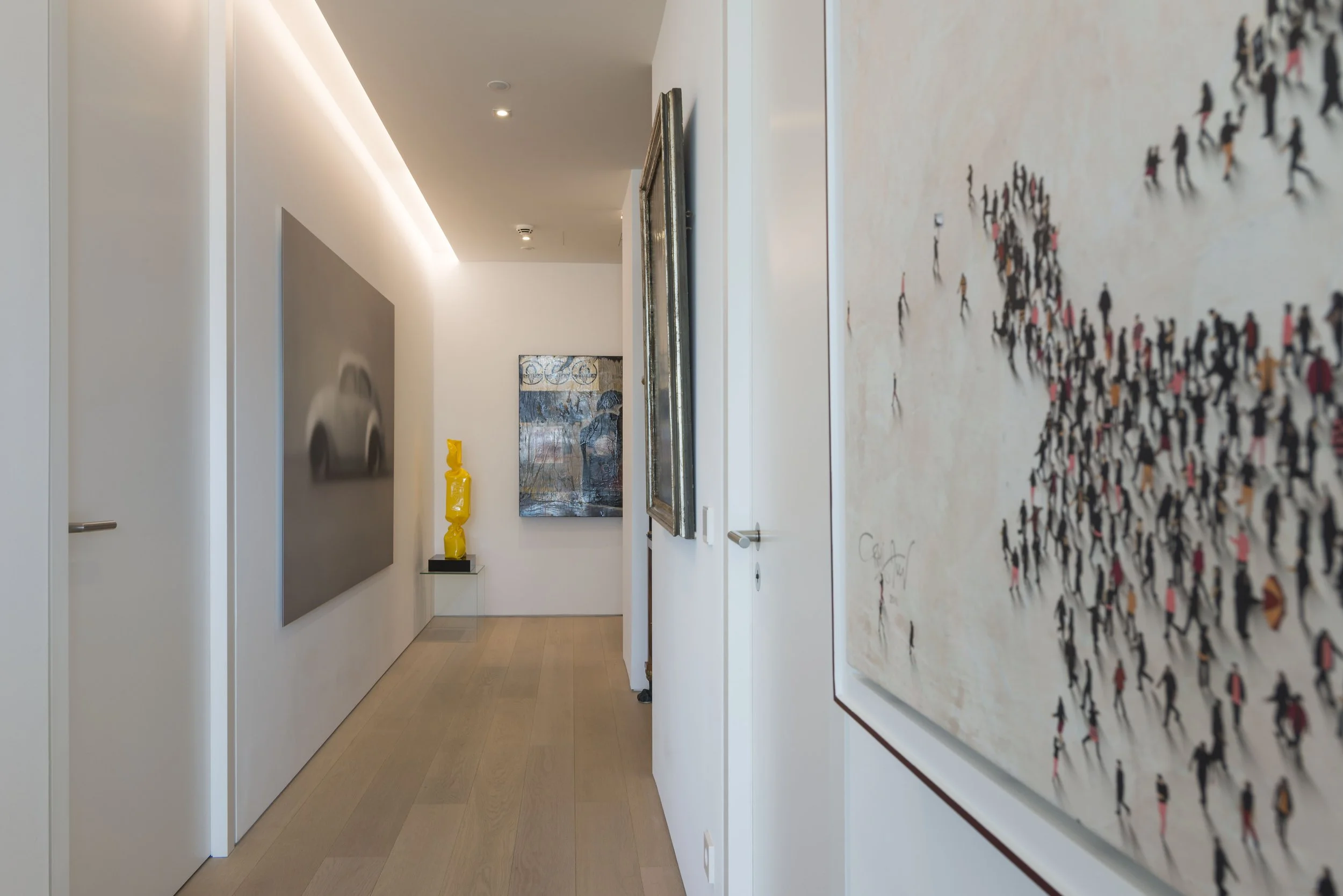 Galerie mit weißen Wänden, mehrere Kunstwerke und Skulpturen, Holzfußboden.