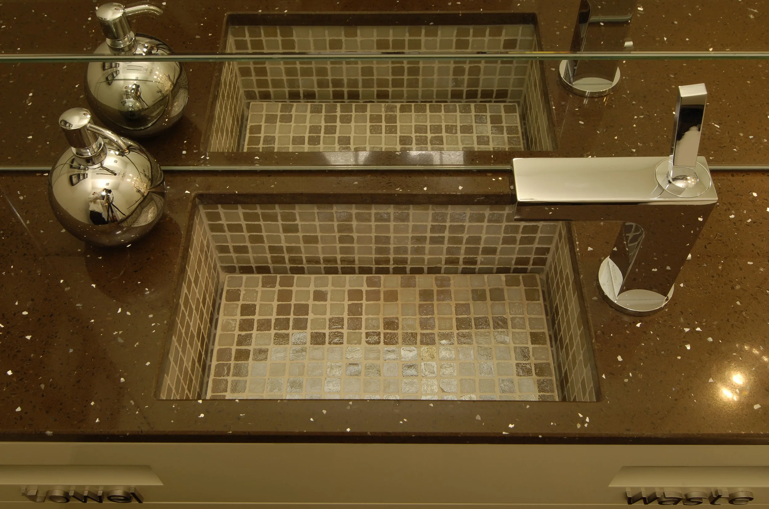 Doppelwaschbecken mit Mosaik-Innenbecken, braune Arbeitsplatte, zwei dekorative silberne Seifenspender, große runde Spiegel