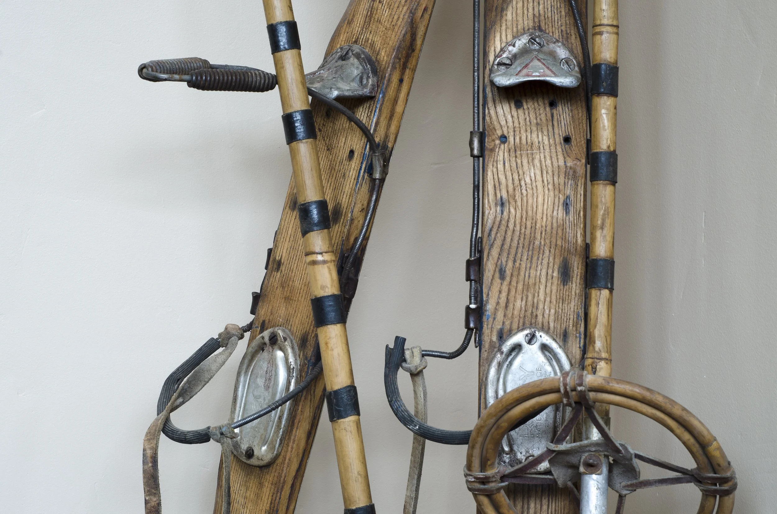 Alte Holz-Schneeschuhe mit Metallplatten und Seilführung, an einer Holzwand. 