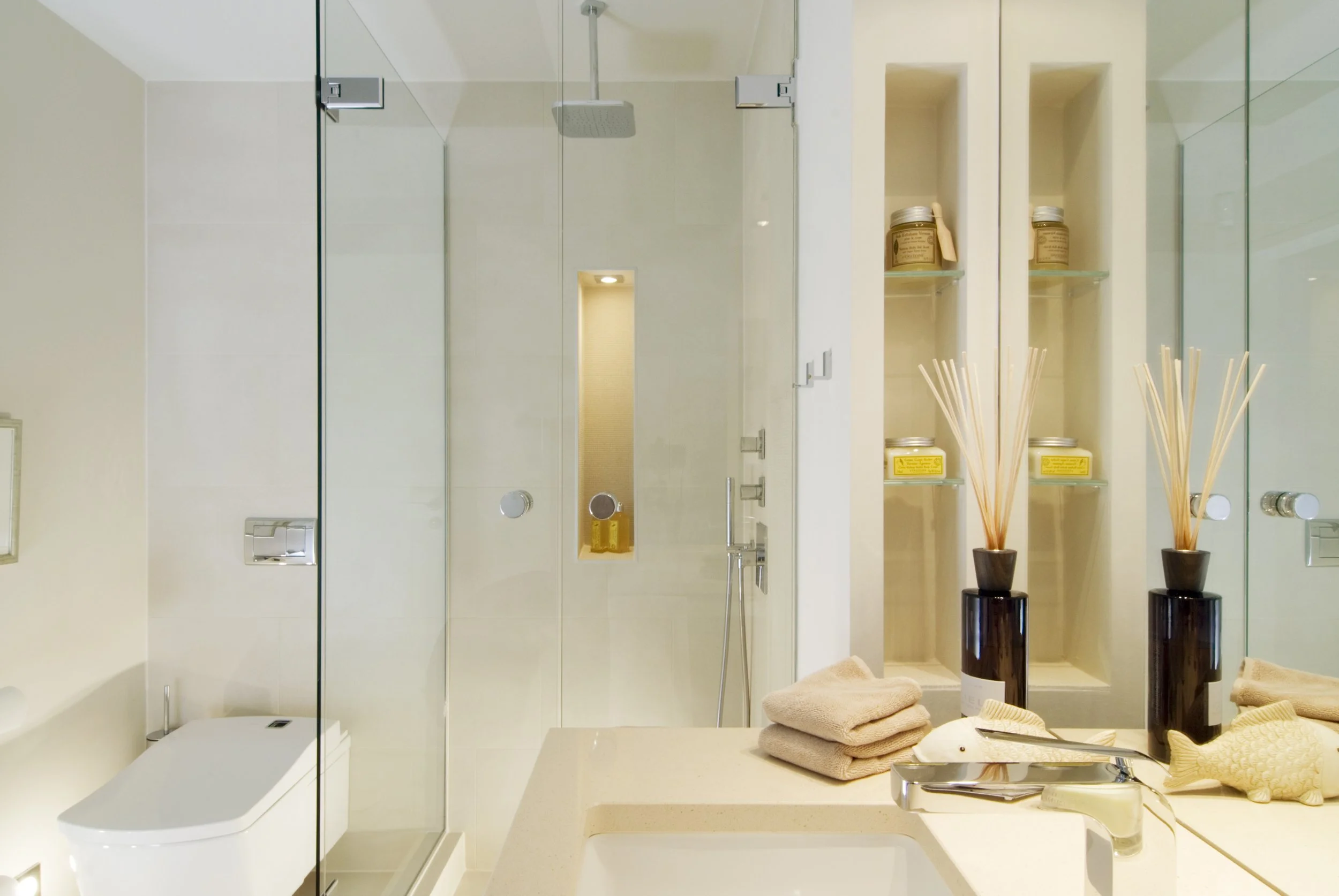 Modernes Badezimmer mit Glasdusche, Badewanne, Spiegel, Handtüchern und Dekorationen.