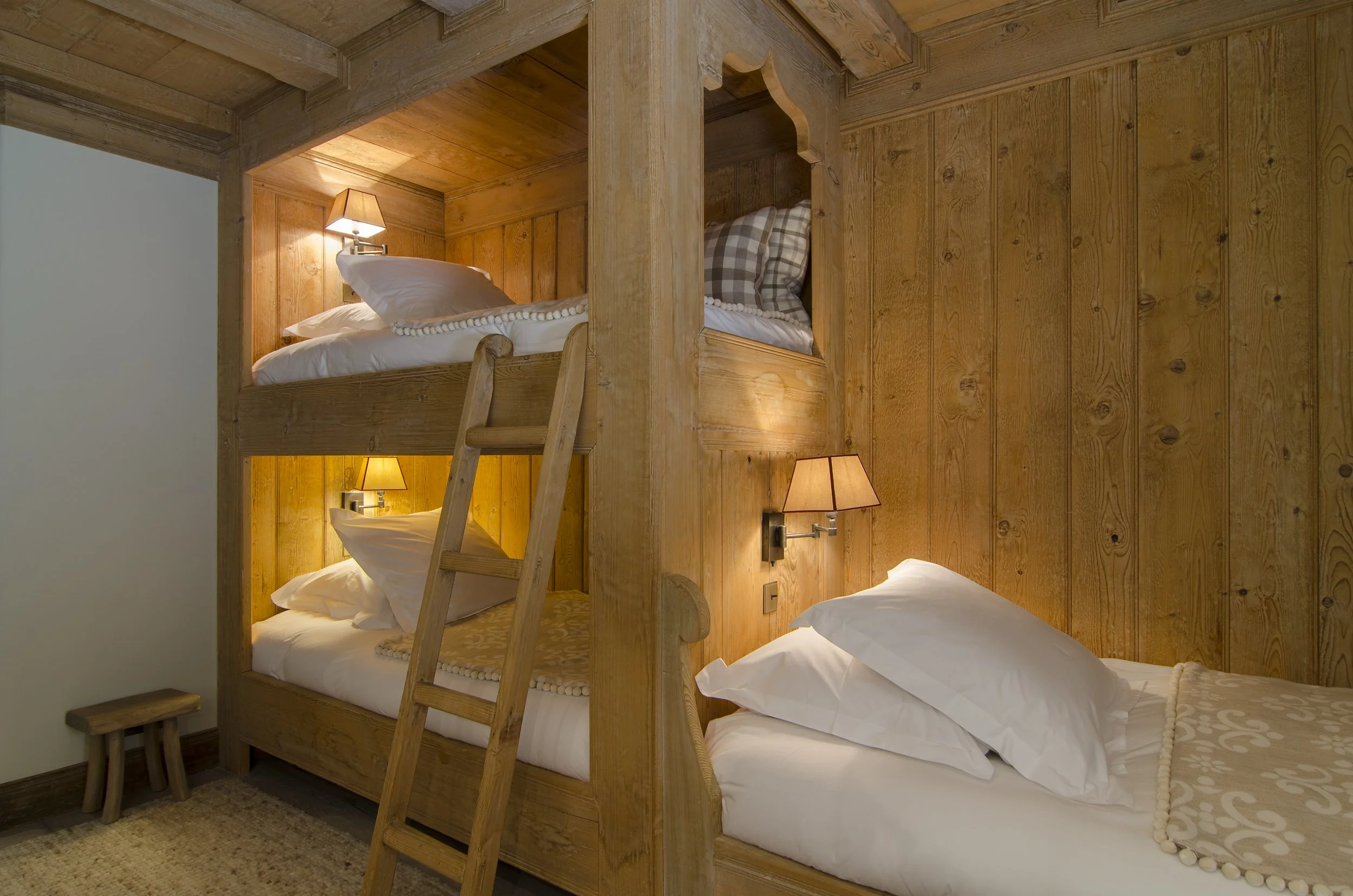Schlafzimmer mit Etagenbetten, Holzvertäfelung und Wandlampen.