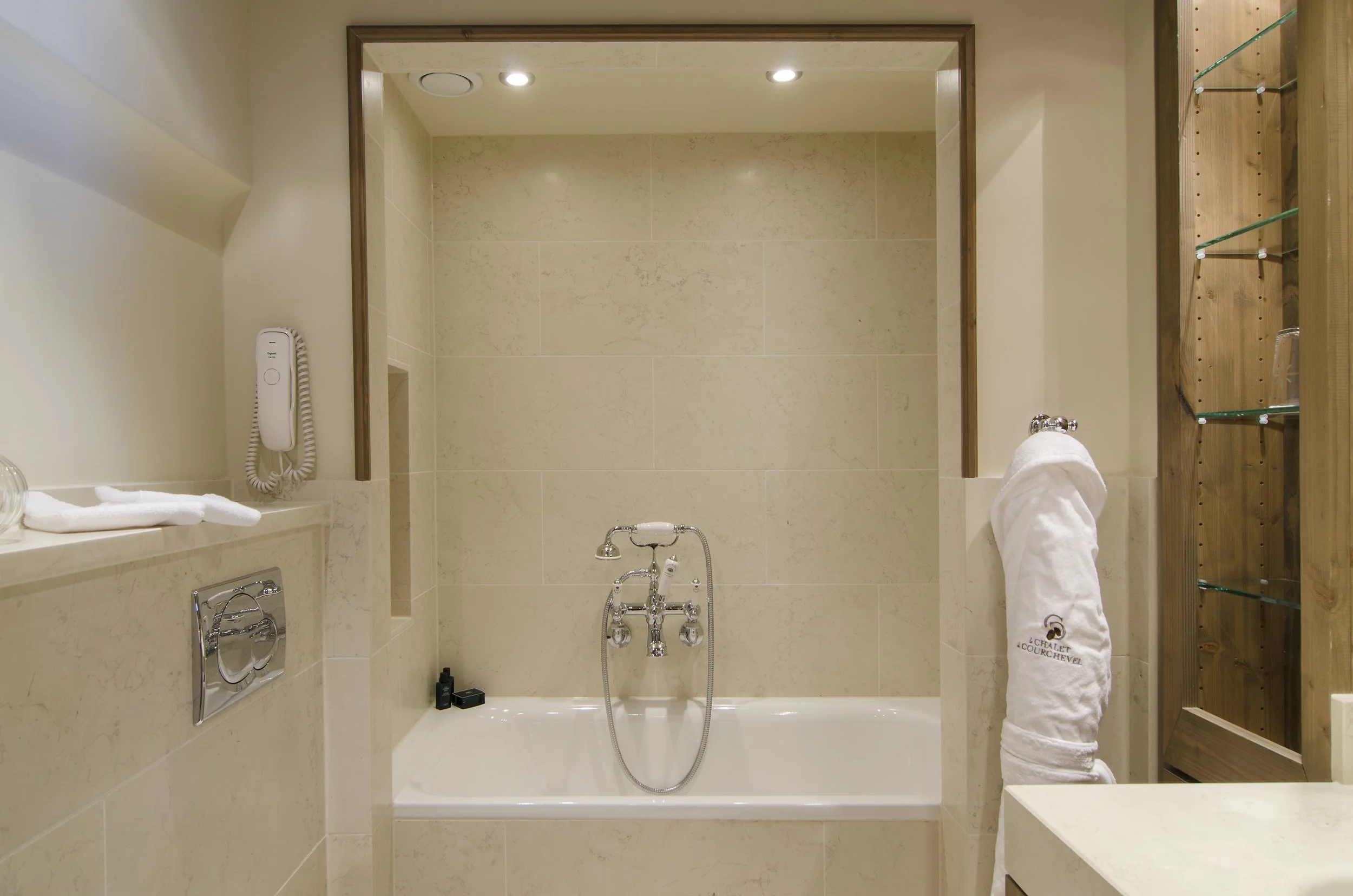 Badezimmer mit Badewanne, Wandheizung, Handtuch, Kosmetikartikeln und Spiegel