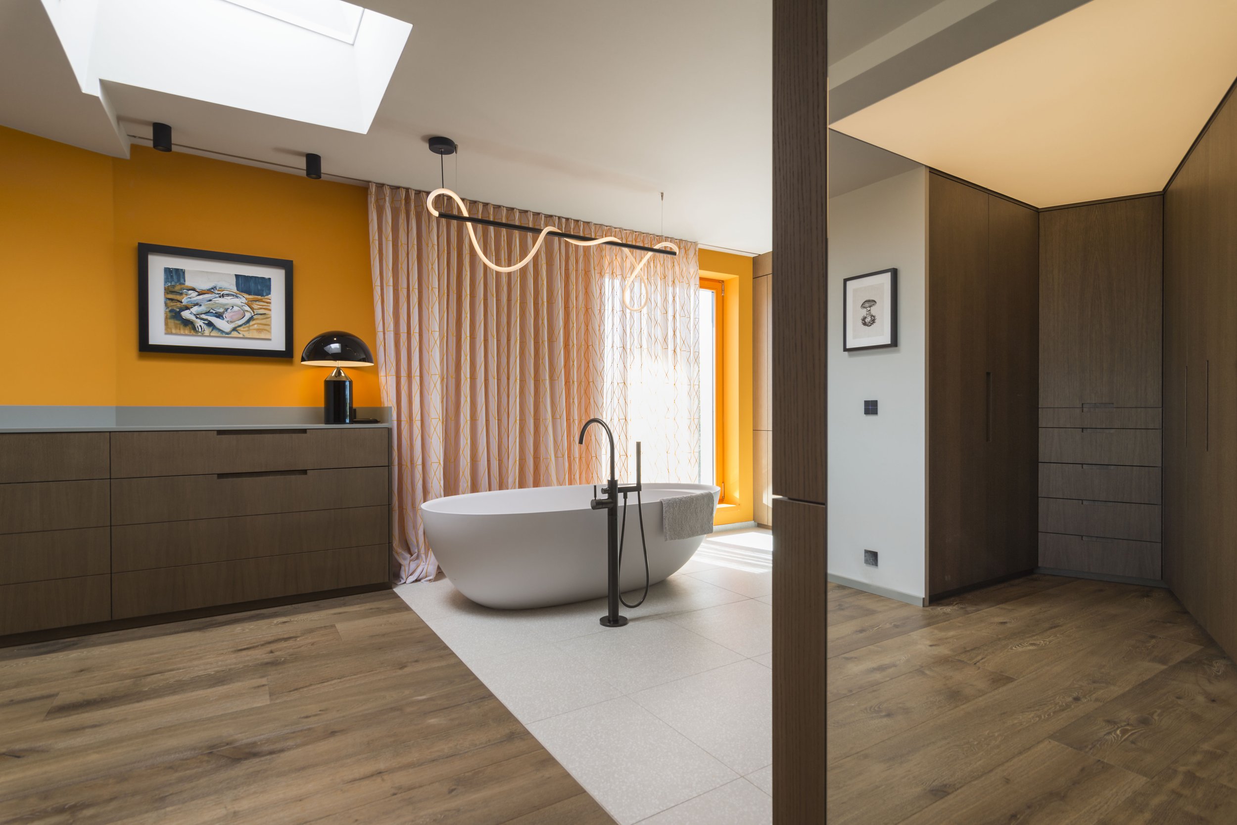 Modernes Badezimmer mit freistehender Badewanne, hölzernen Möbeln, bunten Wänden und Gardinen.