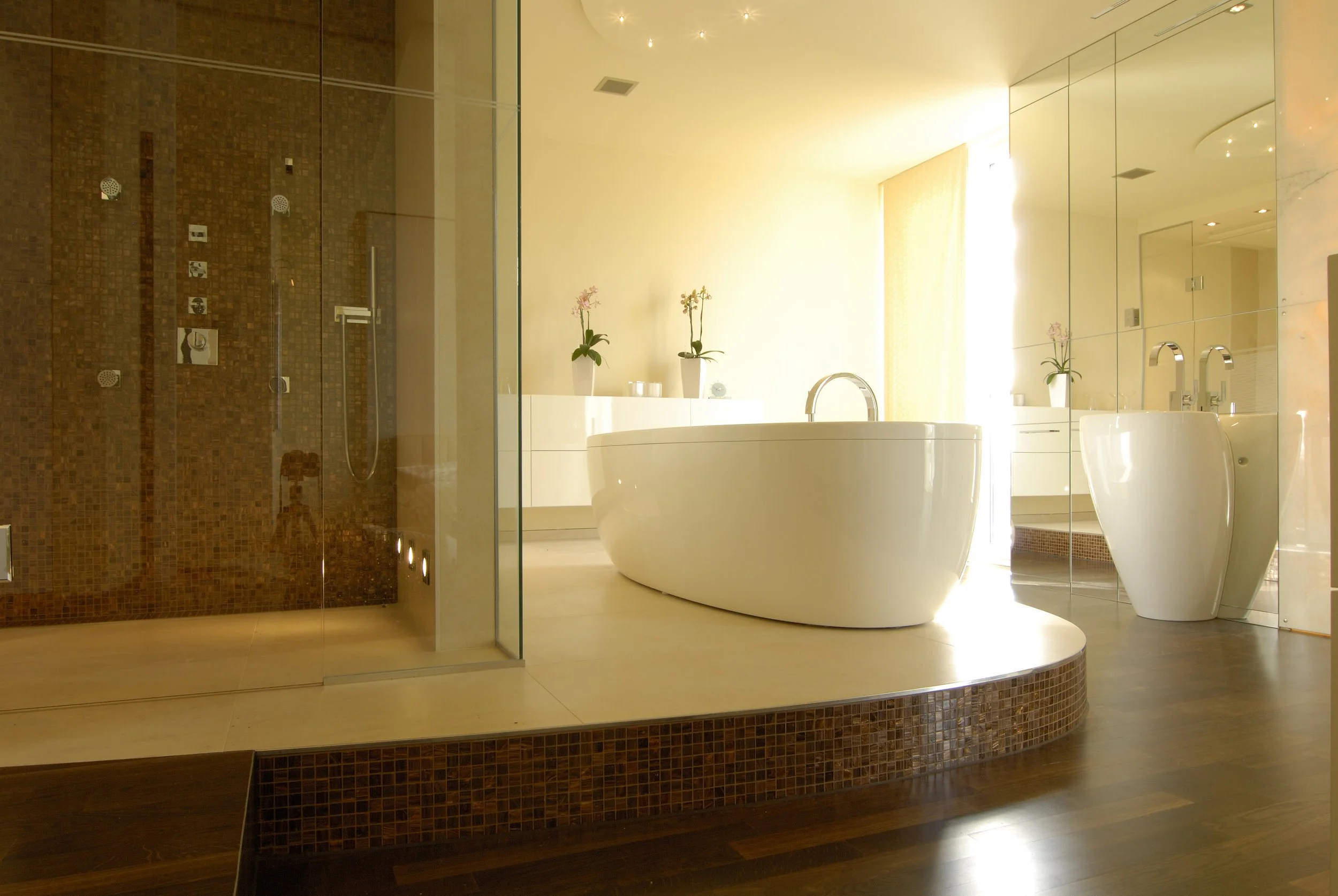 Ein modernes Badezimmer mit freistehender Badewanne, Dusche im offenen Nischen, Zimmerpflanzen und Spiegelwand, helle Wände und Holzboden.