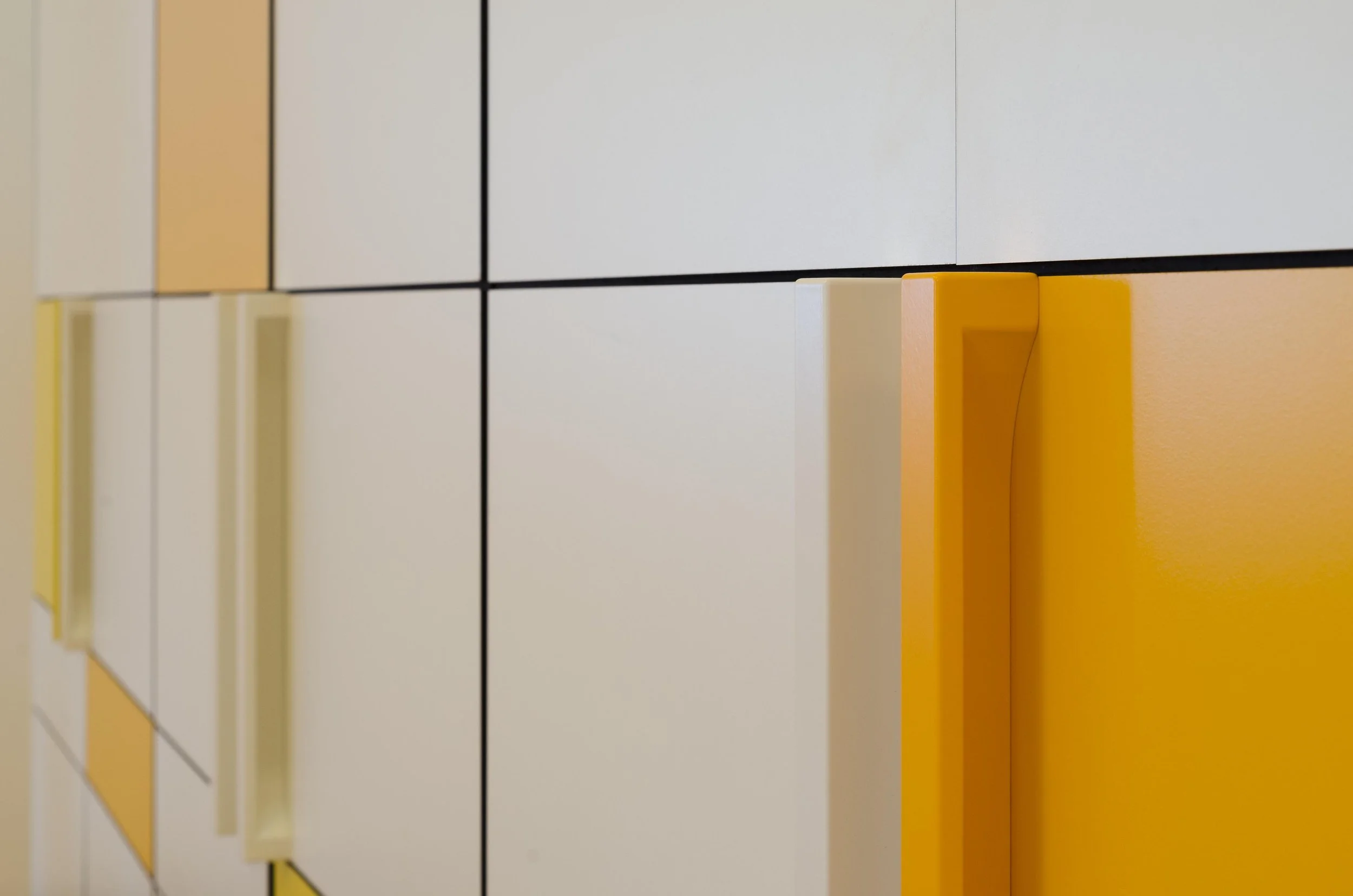 Nahaufnahme der Schubladen mit gelben und weißen Griffen in einem modernen Design.