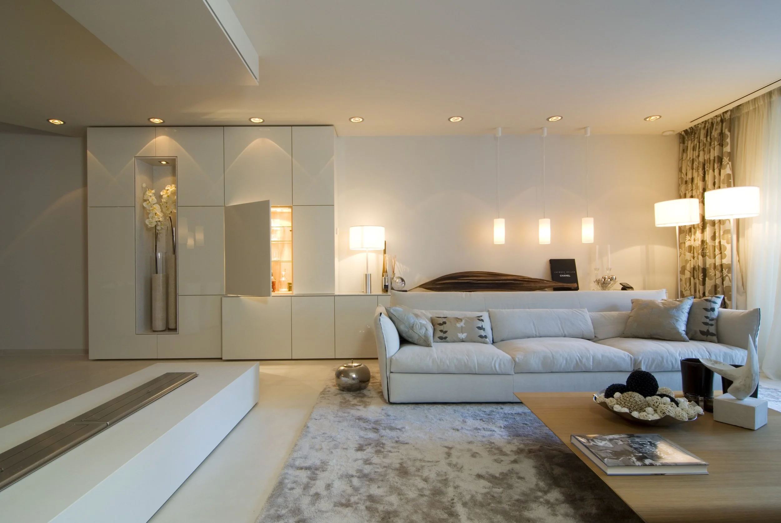 Modernes Wohnzimmer mit weißem Sofa, Holz Couchtisch, Stehlampen, Vorhängen und dekorativen Gegenständen