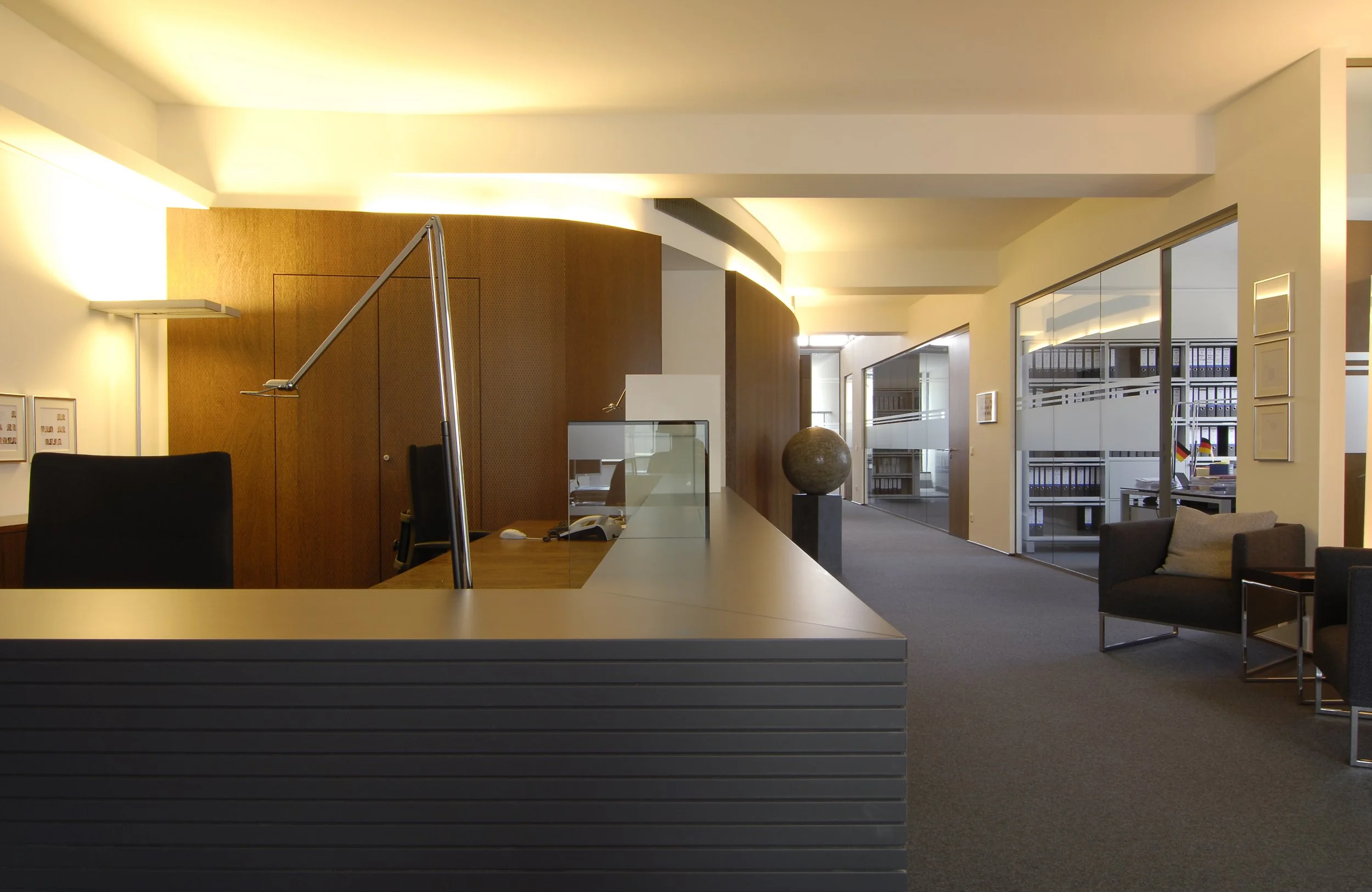 Innenansicht eines modernen Büros mit Empfangstresen, Sitzgelegenheiten und Büroecken.