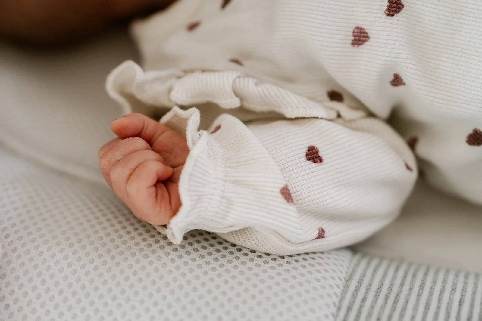Detailfoto van kleine handjes tijdens een newborn sessie in de vertrouwde thuisomgeving.
