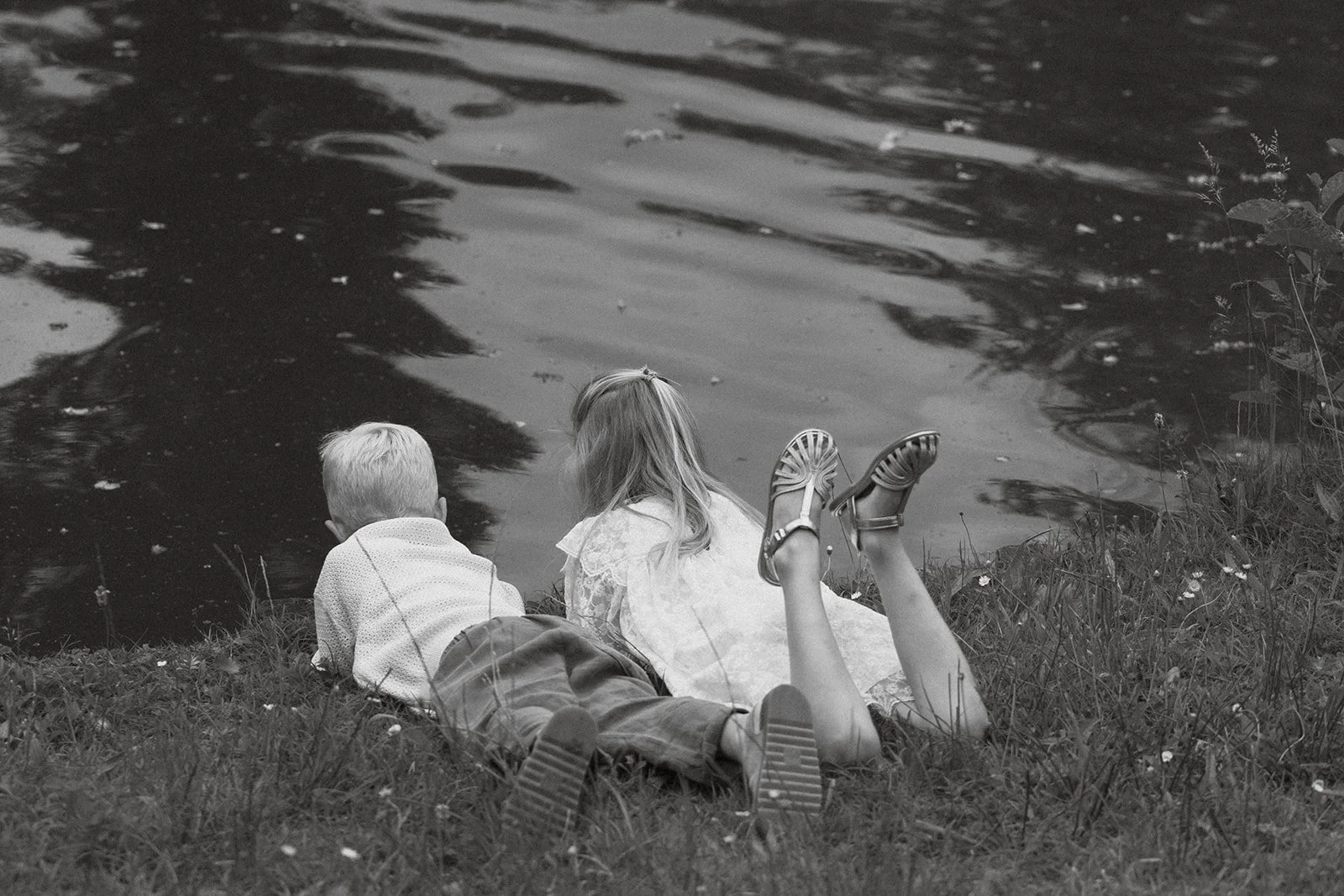 Broer en zus kijken samen uit over de vijver tijdens een natuurlijke familieshoot.