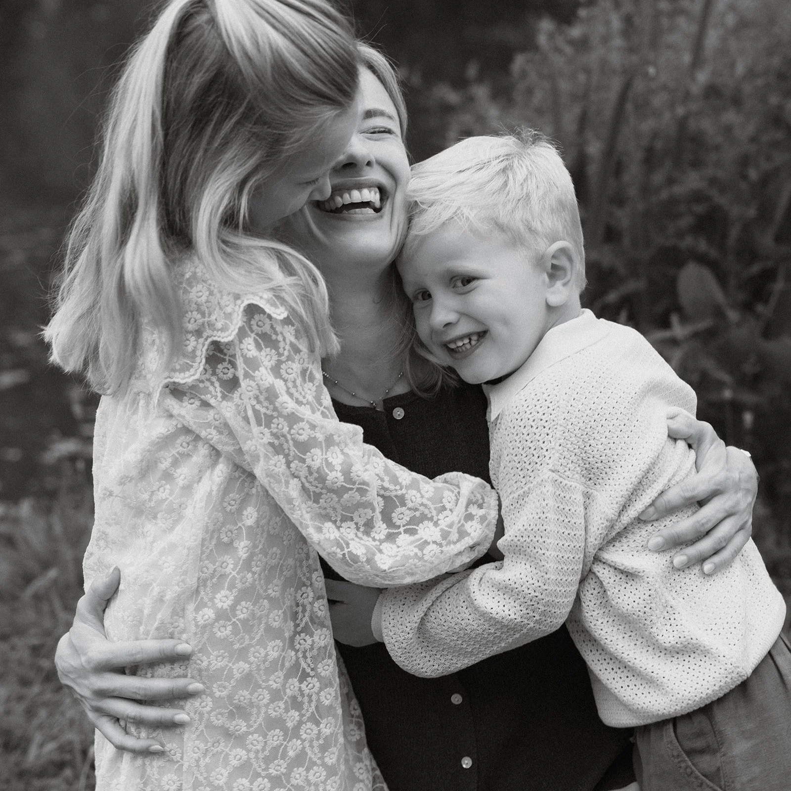 moeder en kinderen in een innige omhelzing tijdens een ontspannen familiereportage