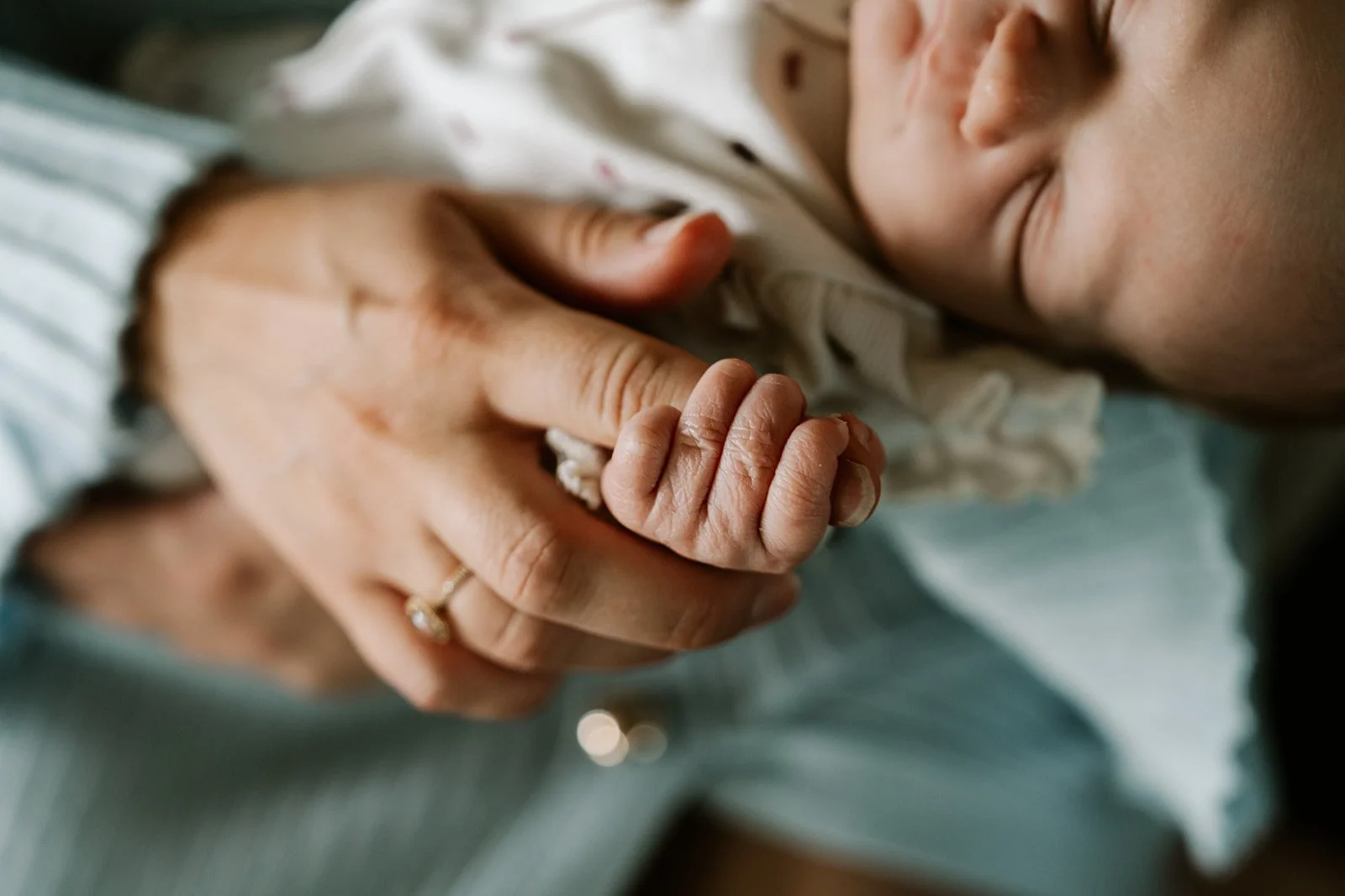 detailfoto van babyhandje en hand van de mama tijdens een Newborn shoot aan huis