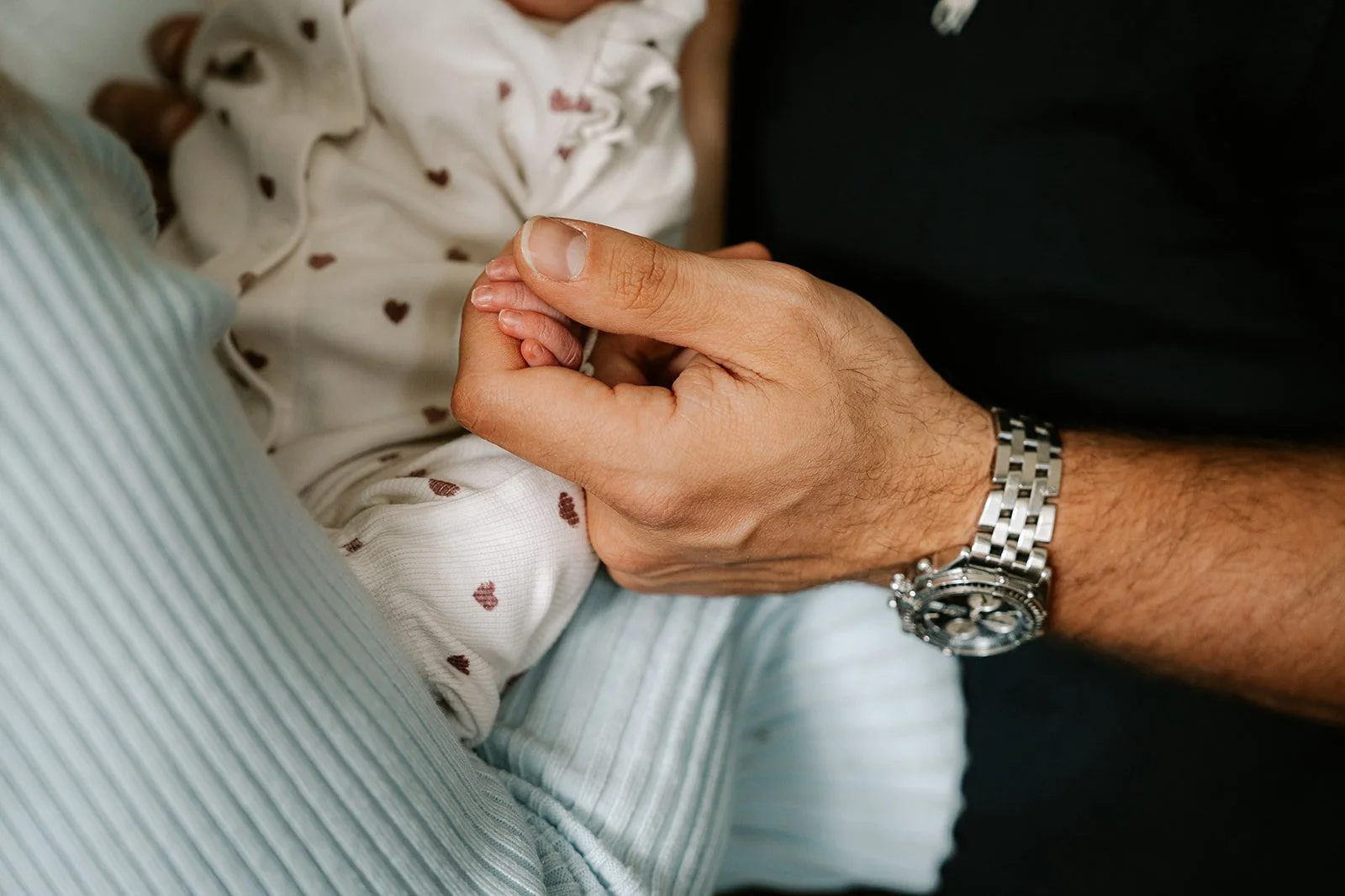 detailfoto van de handen van vader en pasgeboren dochter