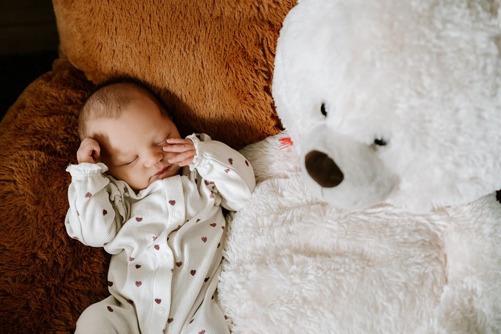 Pasgeboren baby slaapt rustig tussen zachte dekens en knuffeldieren.