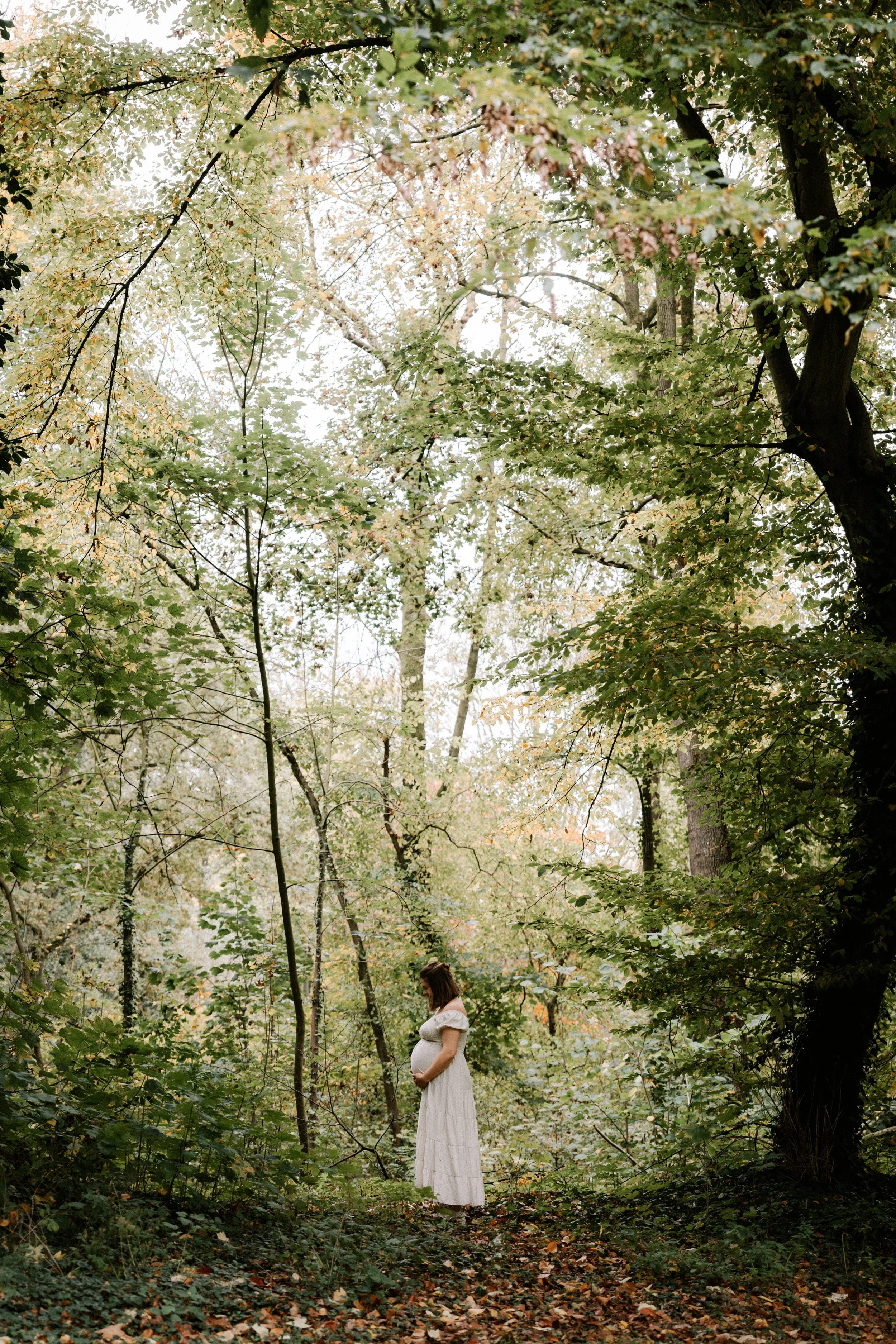 pregnant woman standing in nature holding her belly