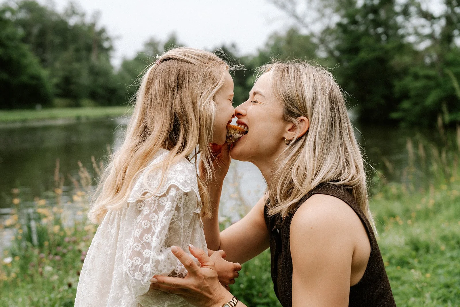 Moeder en dochter delen een warm moment tijdens een fotoshoot in de natuur.