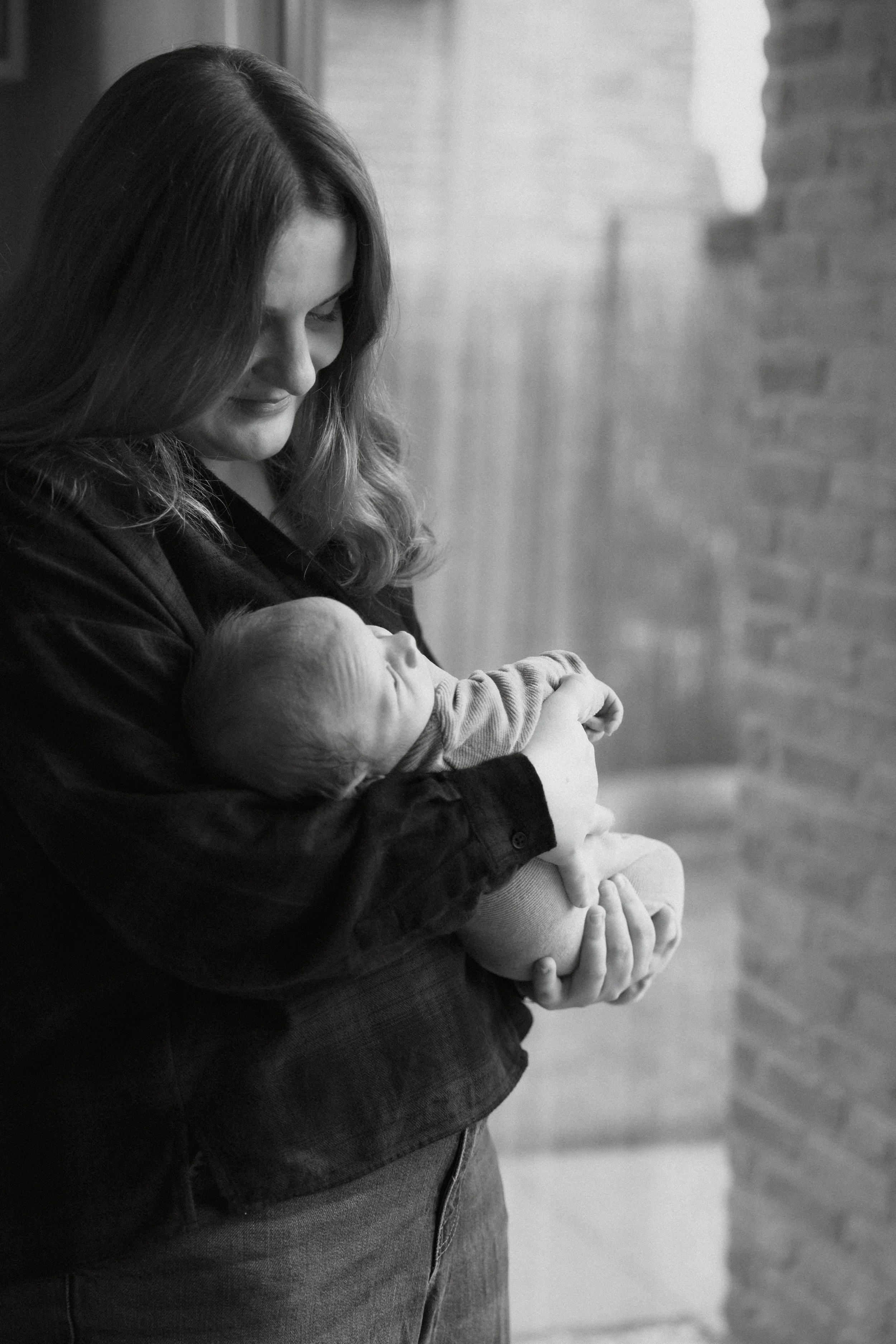 young woman holding her newborn baby at home during a relaxed photoshoot