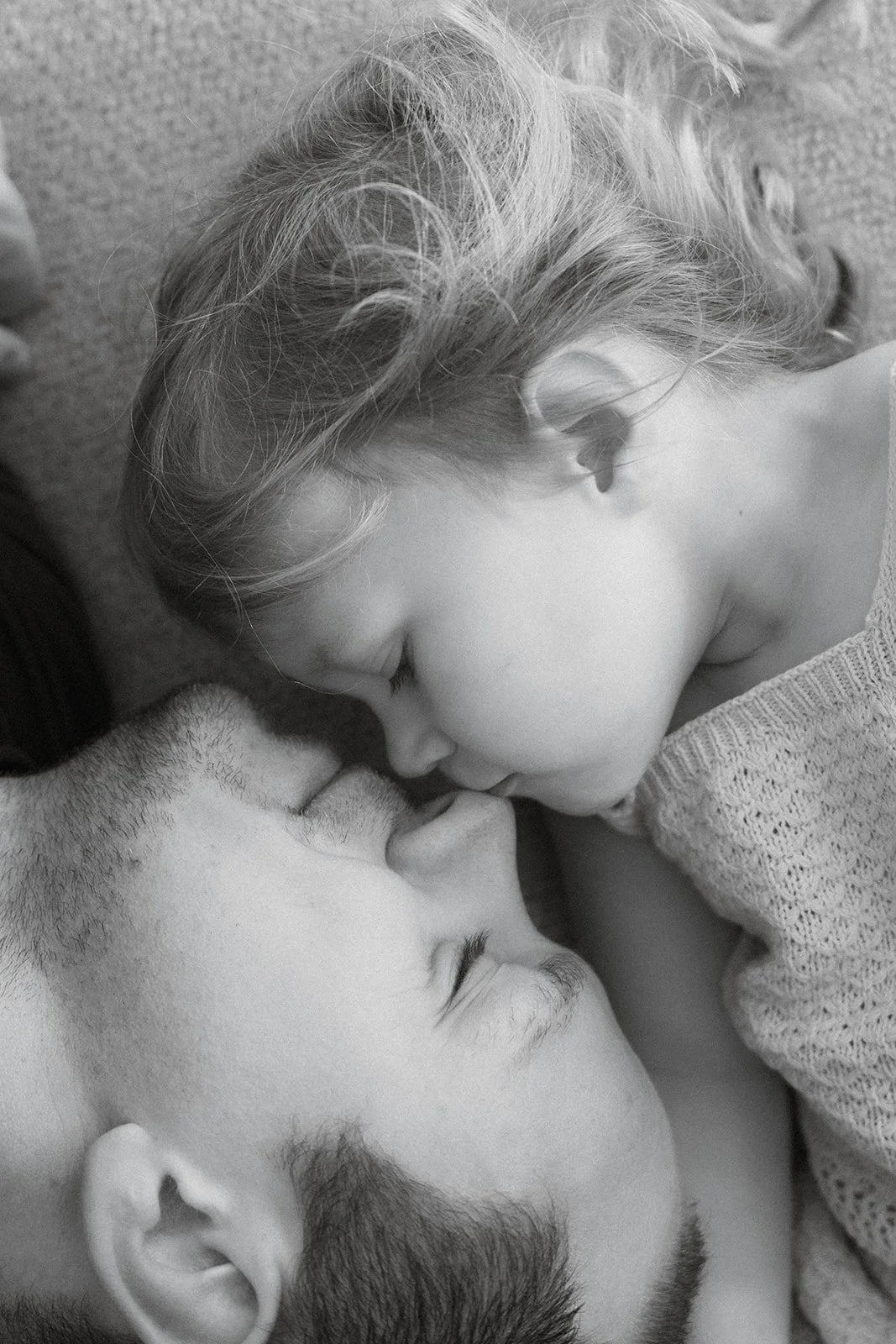 dochter geeft een kus op de neus van vader tijdens een fotoshoot aan huis