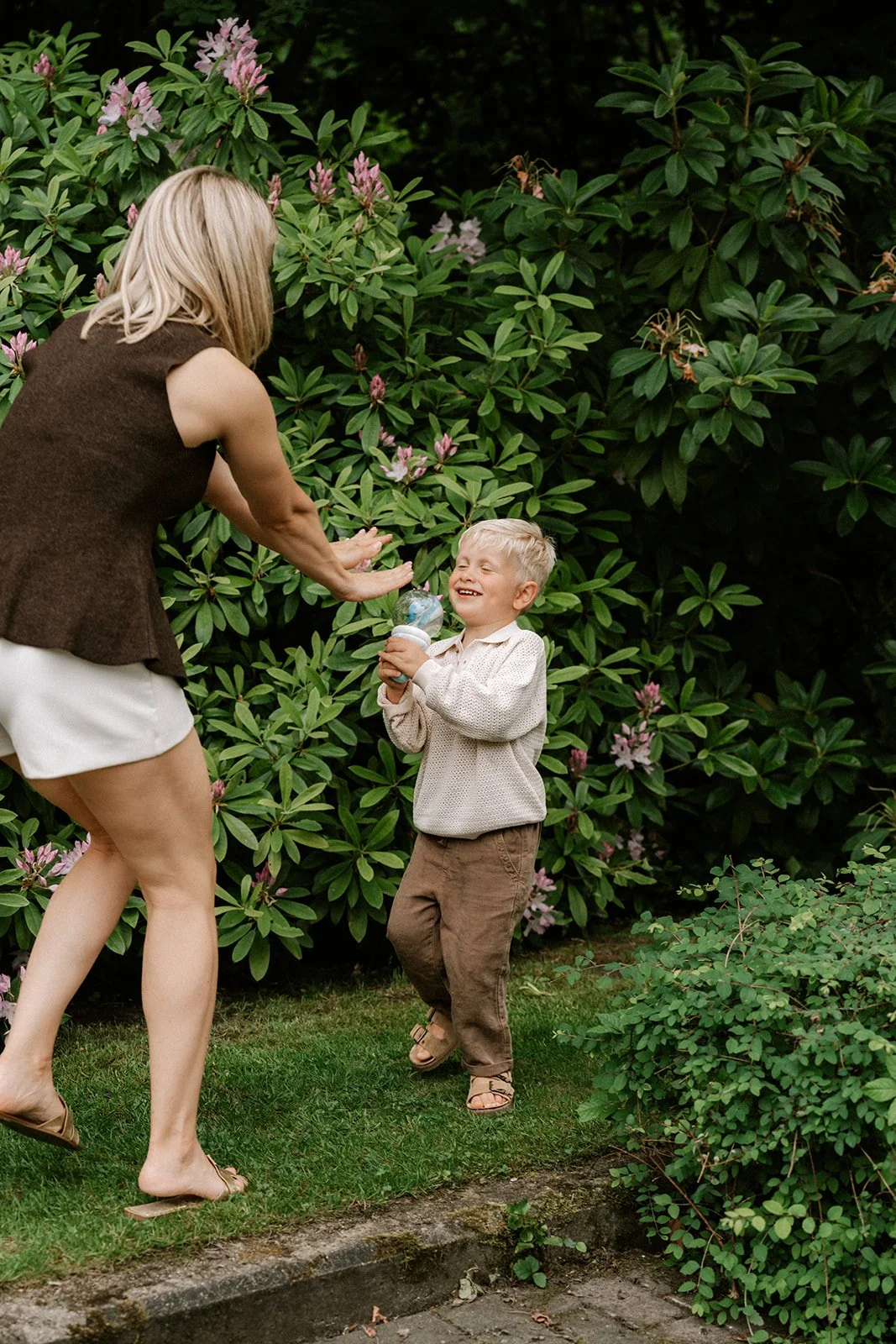 Moeder en zoon spelen met water tijdens een familiesessie in de Vlaamse Ardennen