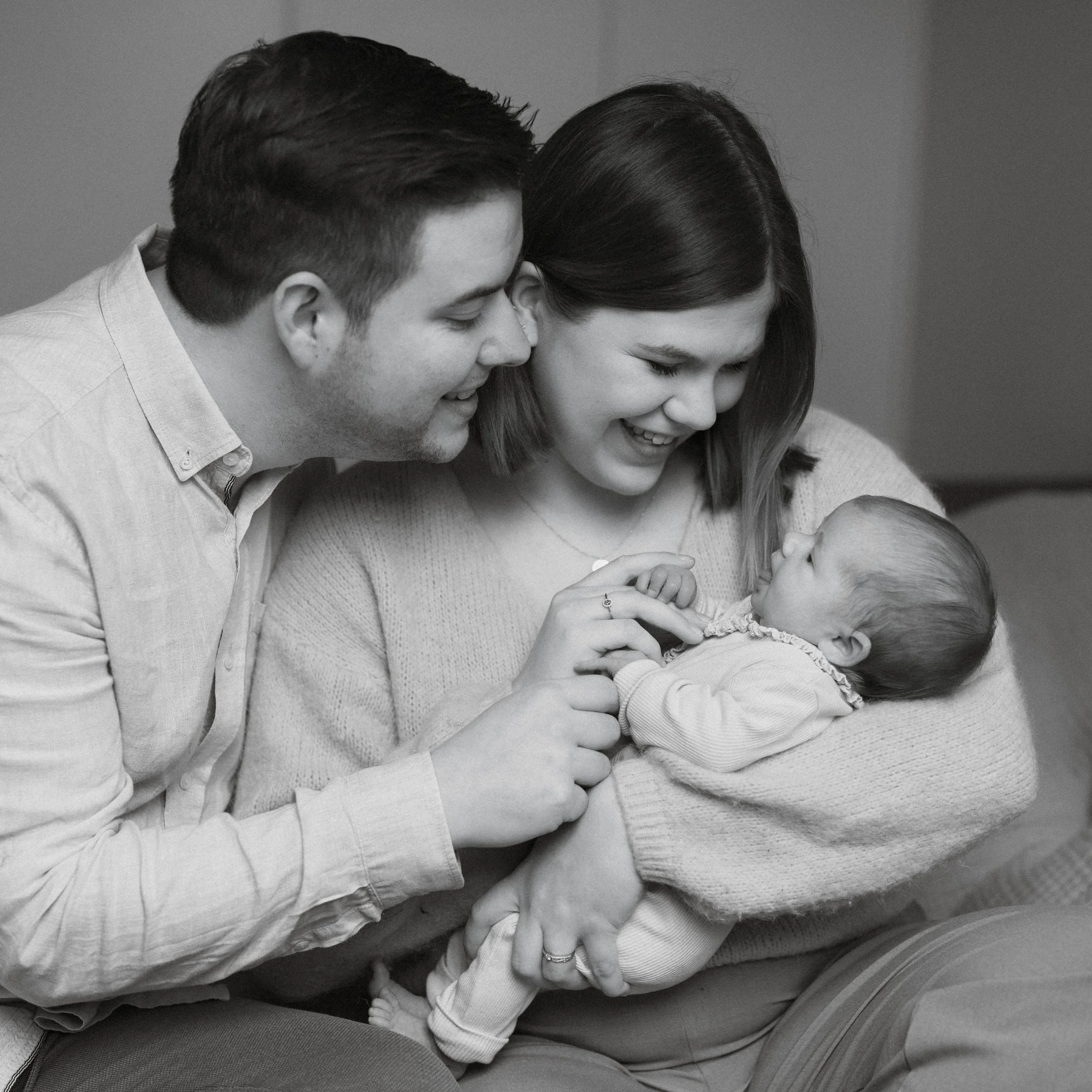 parents holding their newborn in their own living room