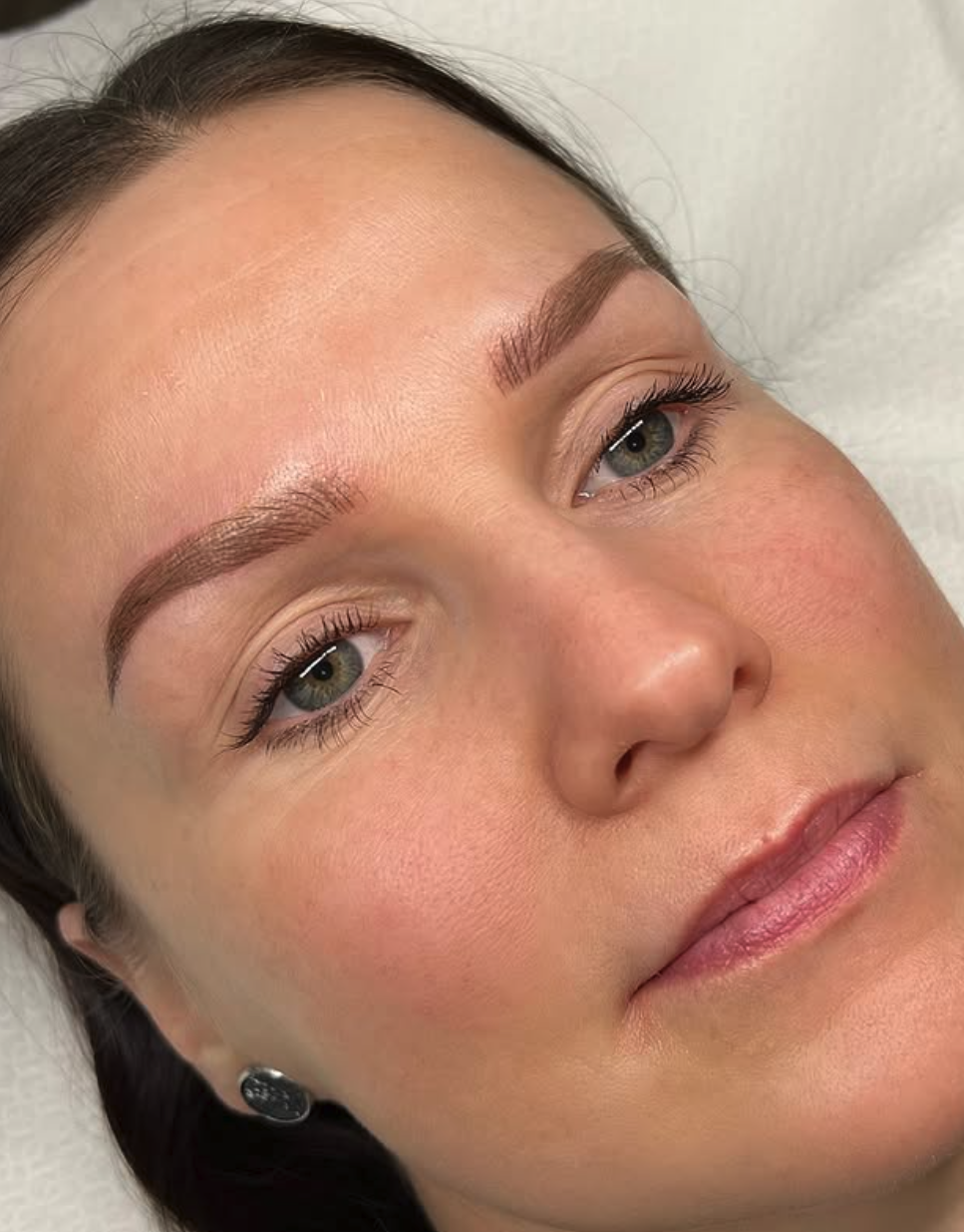 Lähikuvassa naisen kasvot, joihin on juuri tehty microblading tai puuterikulmat käsittely.