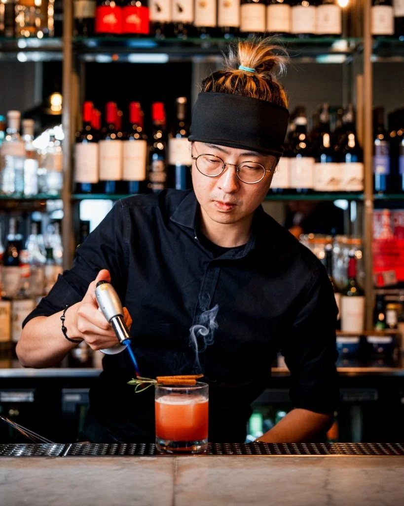 A bartender using a blow torch on a cocktail at The Ginger Pig