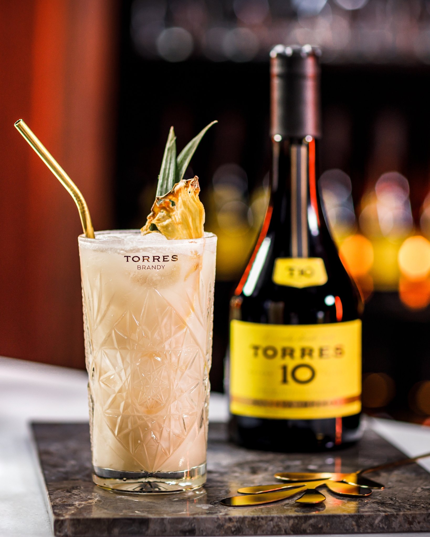 A bottle of Torres Brandy next to a cocktail.