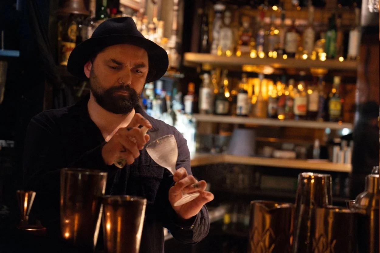A bartender spraying a chilled cocktail glass