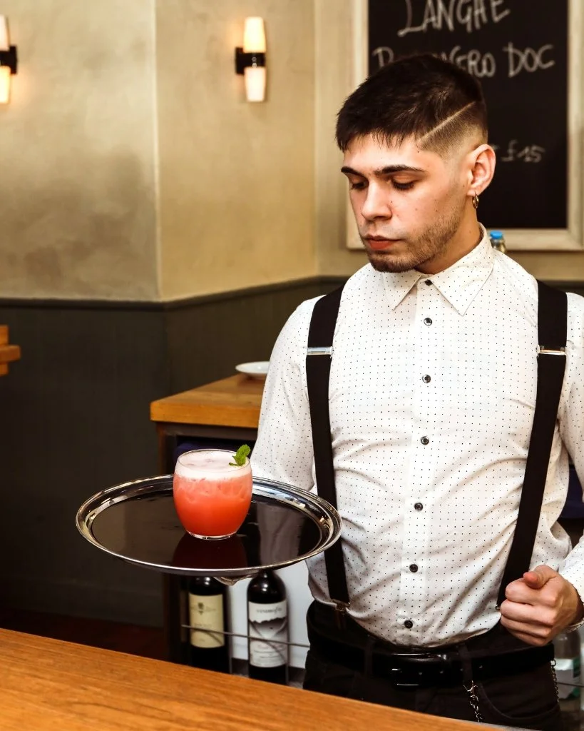 A bartender at Cin Cin holding a tray with a cocktail.