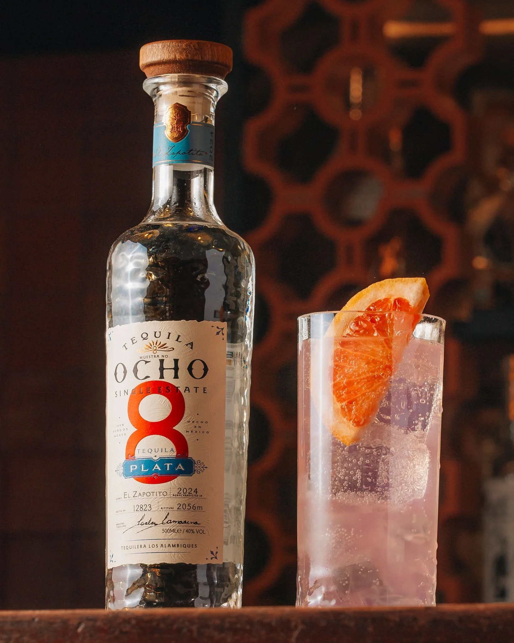 A bottle of Tequila Ocho next to a Paloma cocktail.
