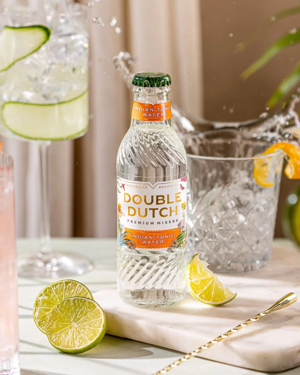 A bottle of Double Dutch Indian Tonic Water with two G&Ts behind it.