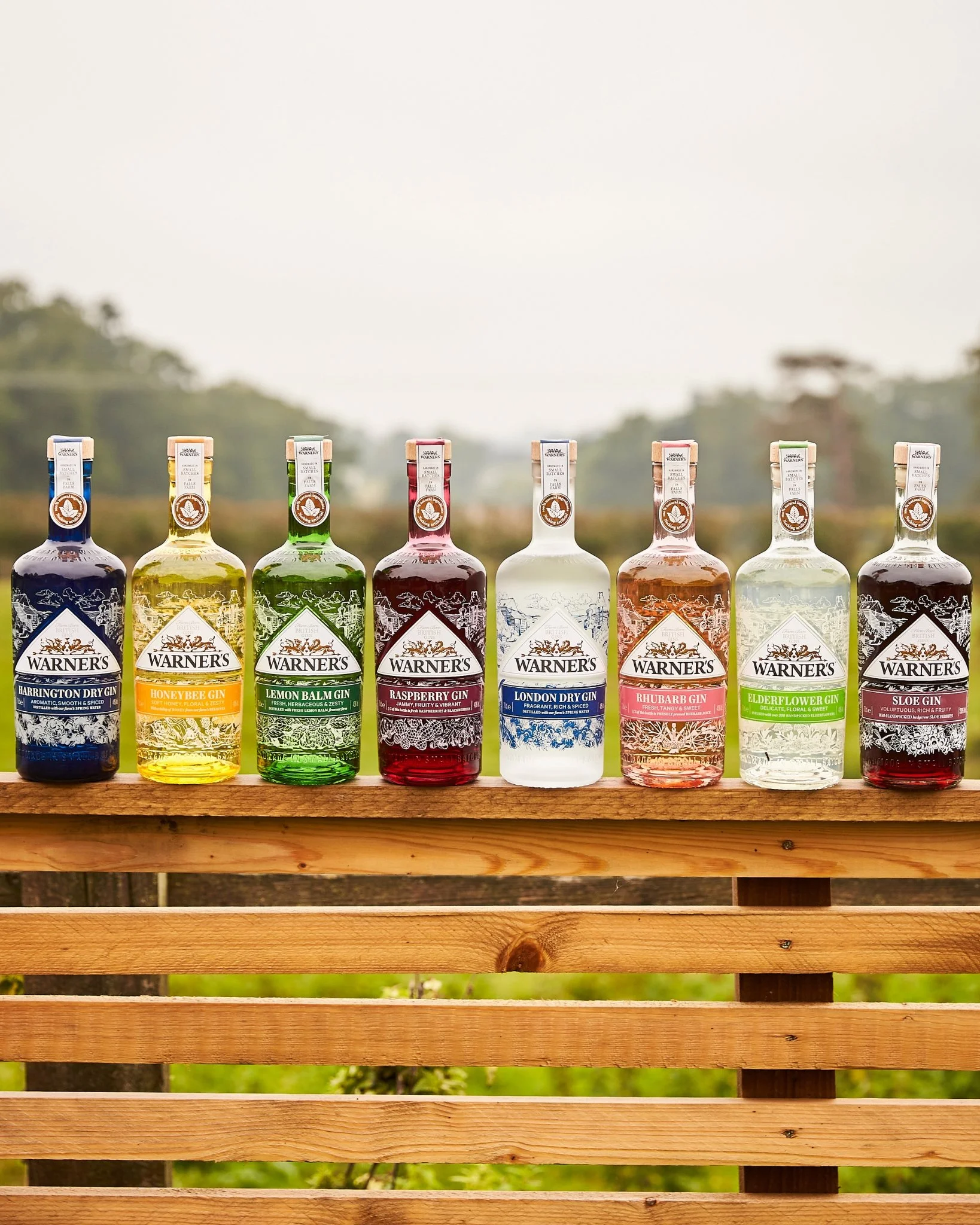 The Warner's Gin range on display on top of a fence in a field.