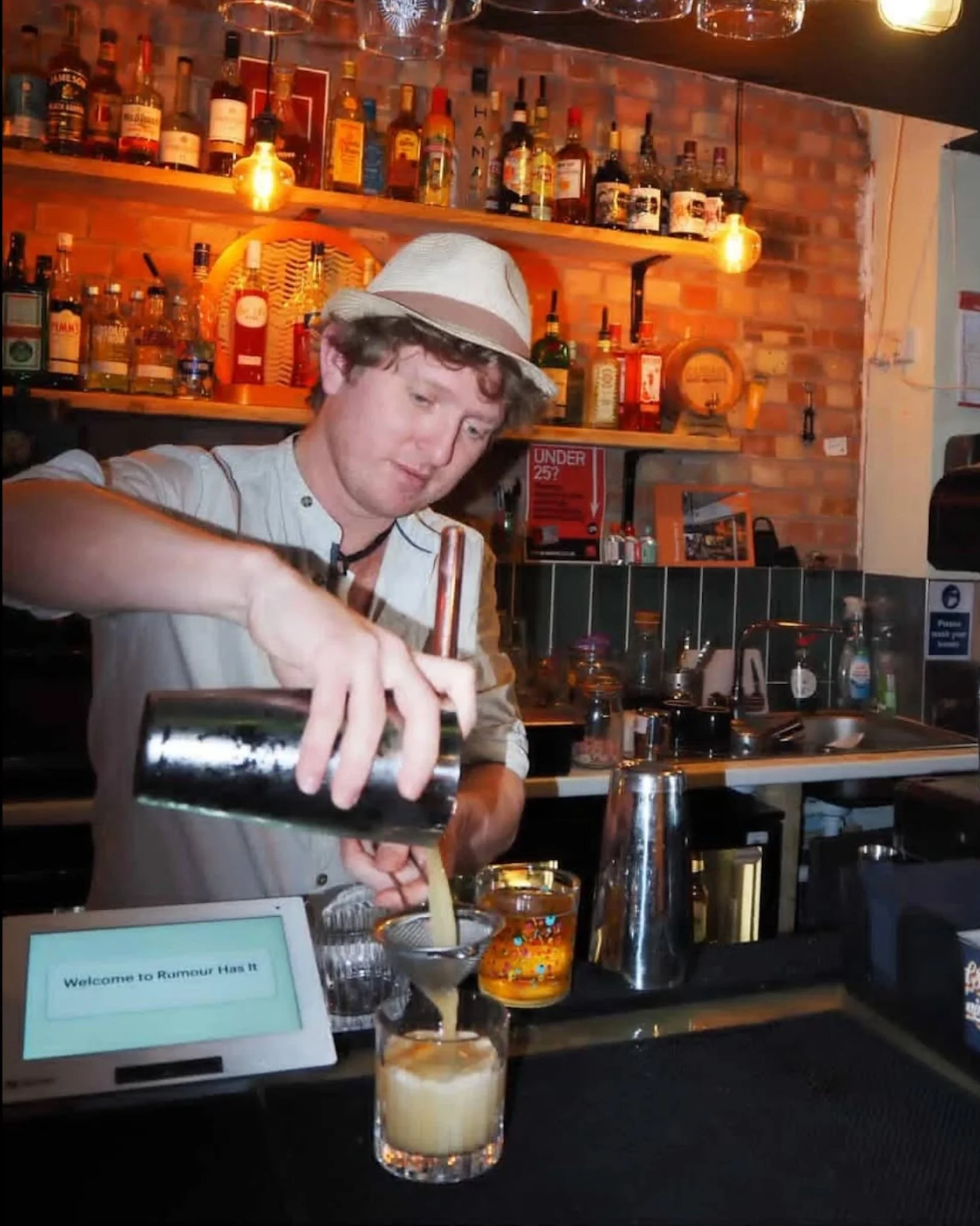 A bartender pouring a cocktail at Rumour has it