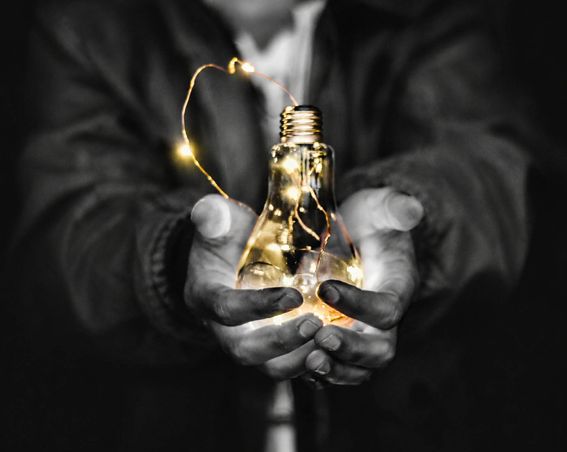 A man in greyscale holding a light shining gold