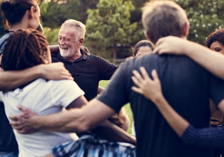 several people in a circle with their arms around one another laughing