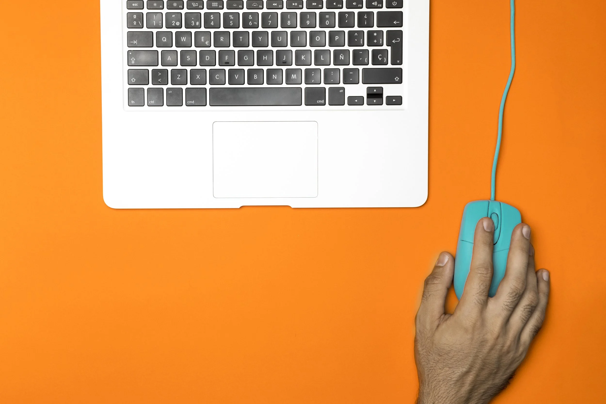 Hand using a computer mouse beside a laptop to illustrate website user experience and navigation