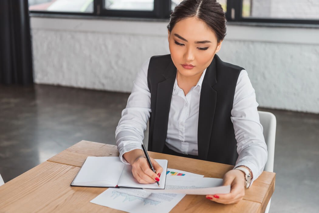 Focused woman in a black vest reviewing documents